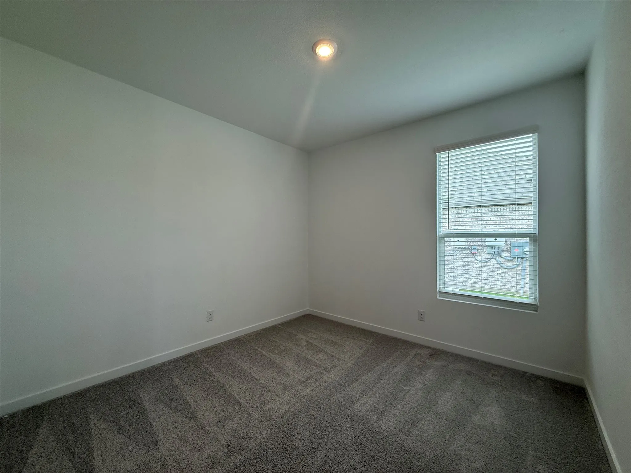 Recessed ceiling light, neutral wall colors, carpet flooring, window with blinds