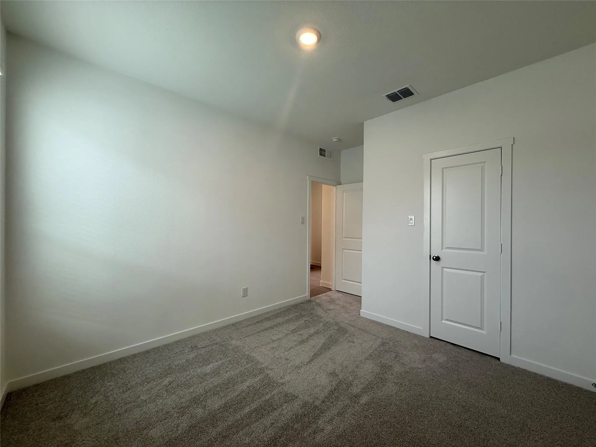 Recessed ceiling light, neutral wall paint, white trim, paneled interior doors, and gray carpeting
