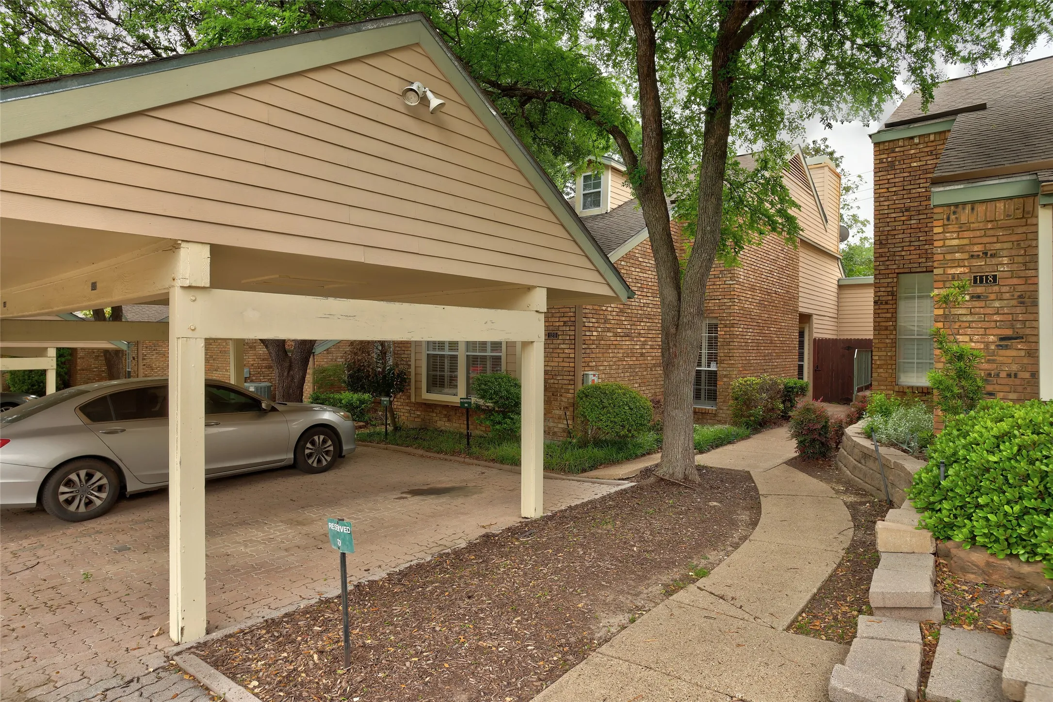 Main entrance on the right side with covered carport.