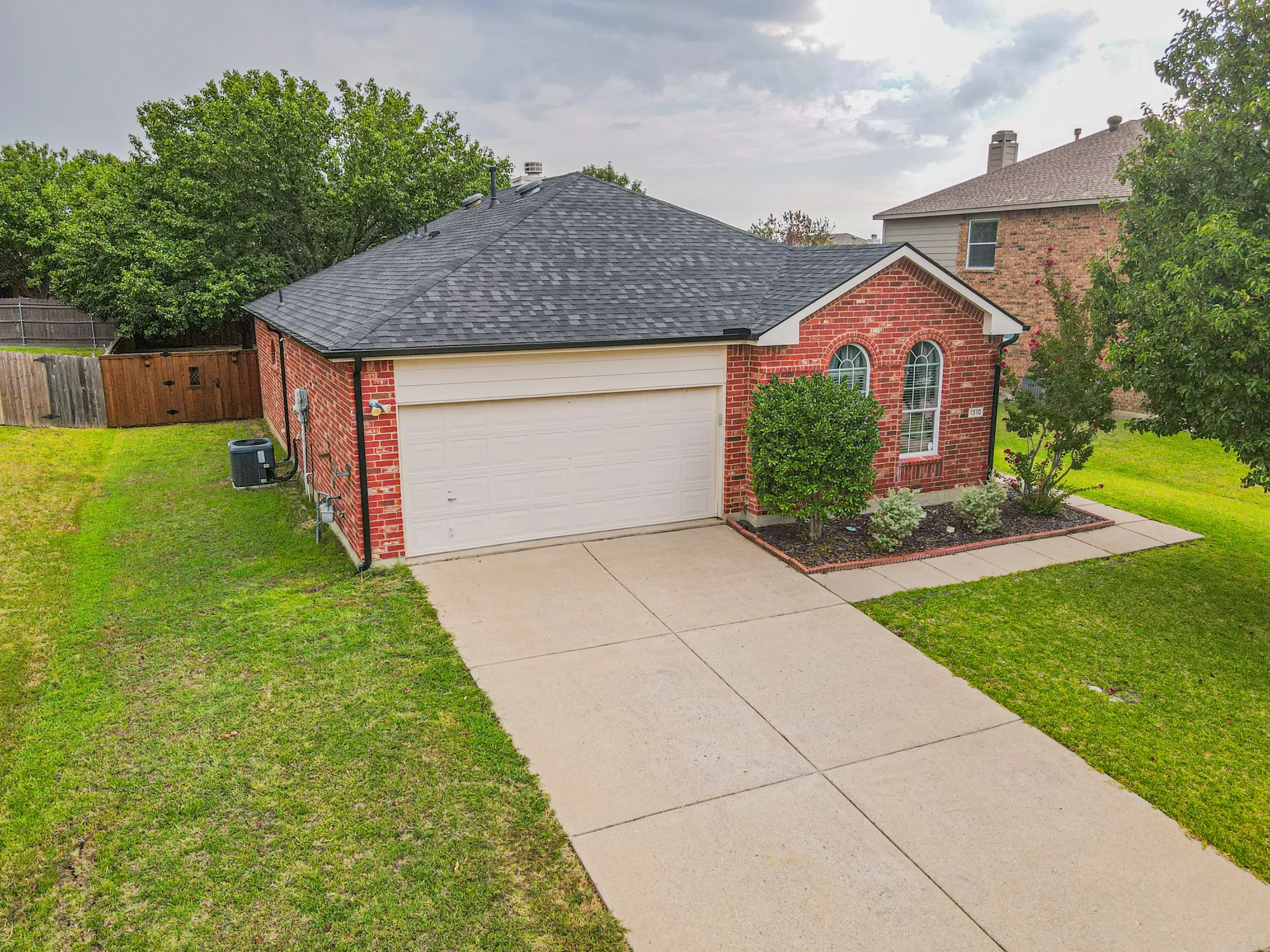 Brick exterior with arched window details, attached garage, and a concrete driveway