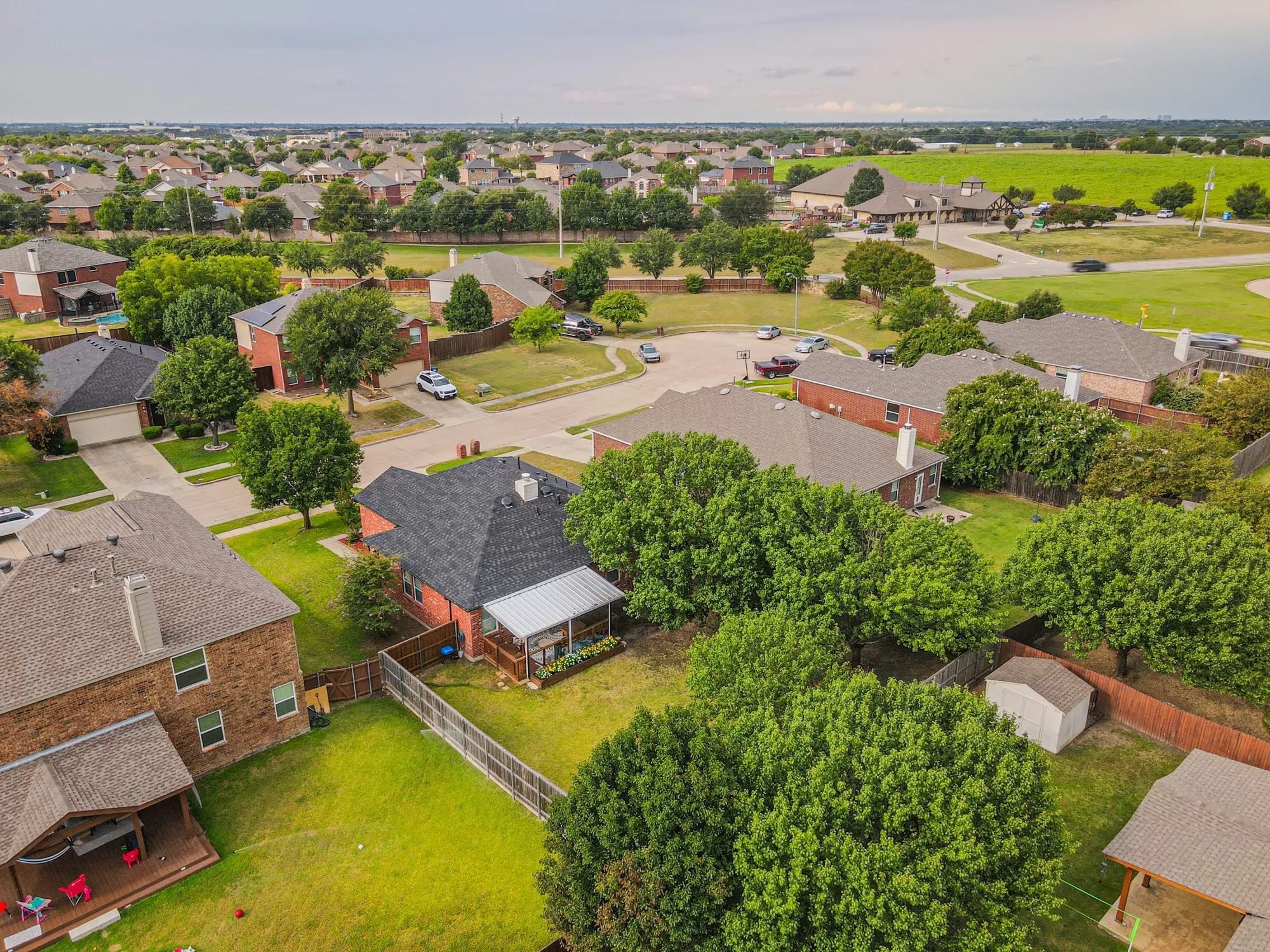 Residential neighborhood with established homes, green spaces, and a paved street