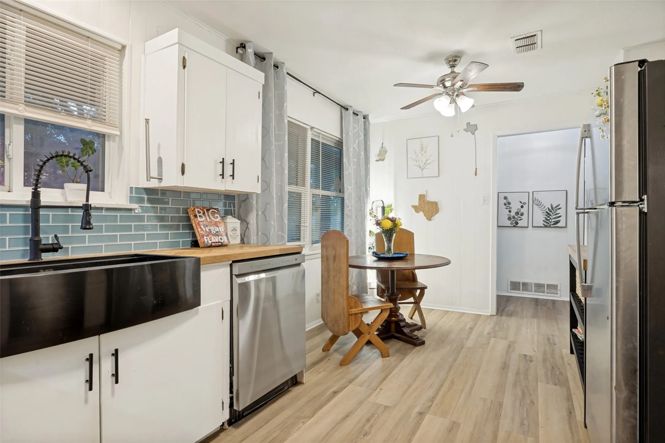 Kitchen with wood-finish flooring, white cabinetry with modern hardware, and a tile backsplash