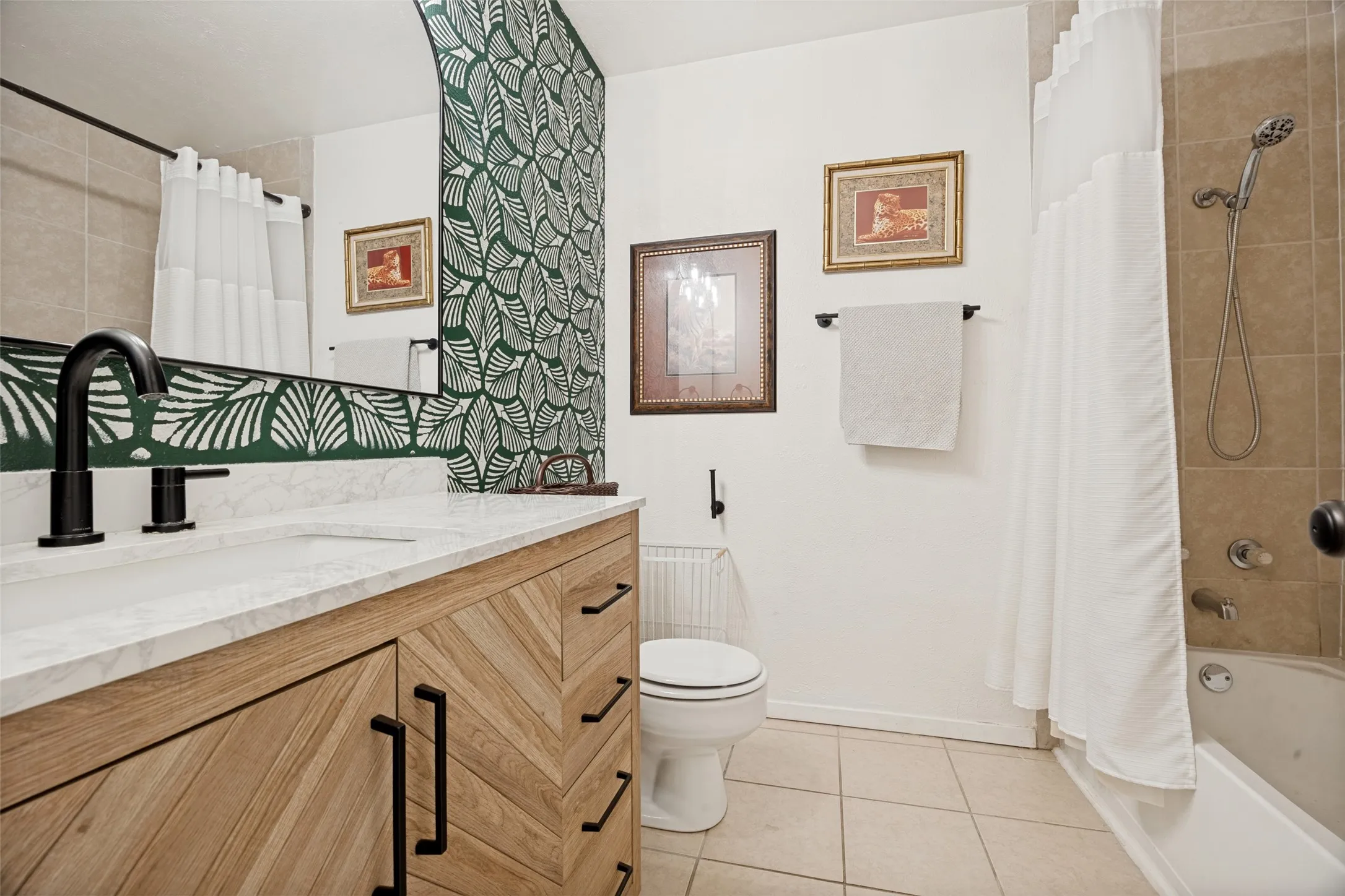 Bathroom featuring a wood-finish vanity with black pulls, a white countertop, a black faucet, and a shower/tub combination with tiled walls