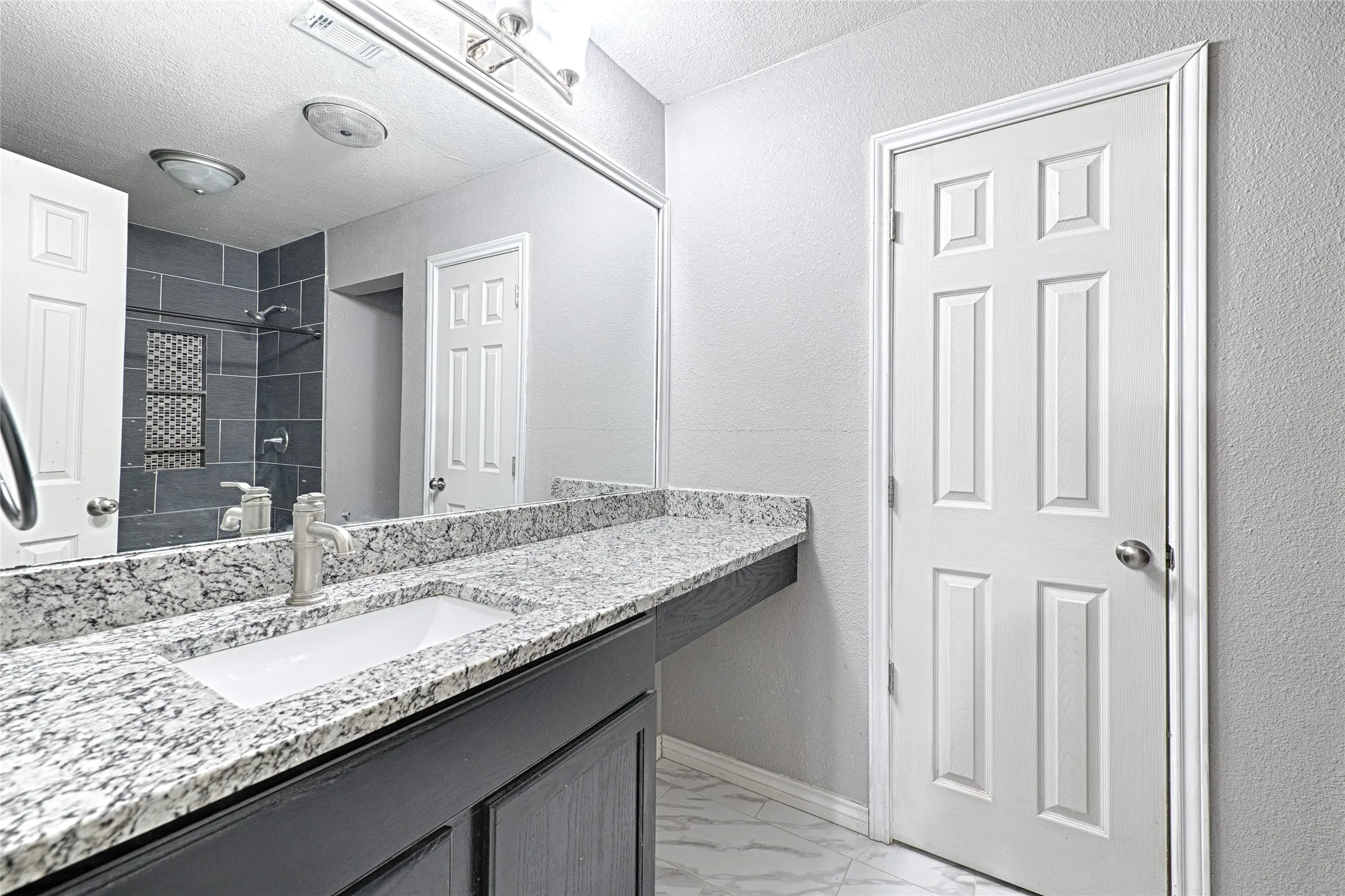Built-in vanity with a rectangular undermount sink, stone-finish countertop, and brushed nickel faucet