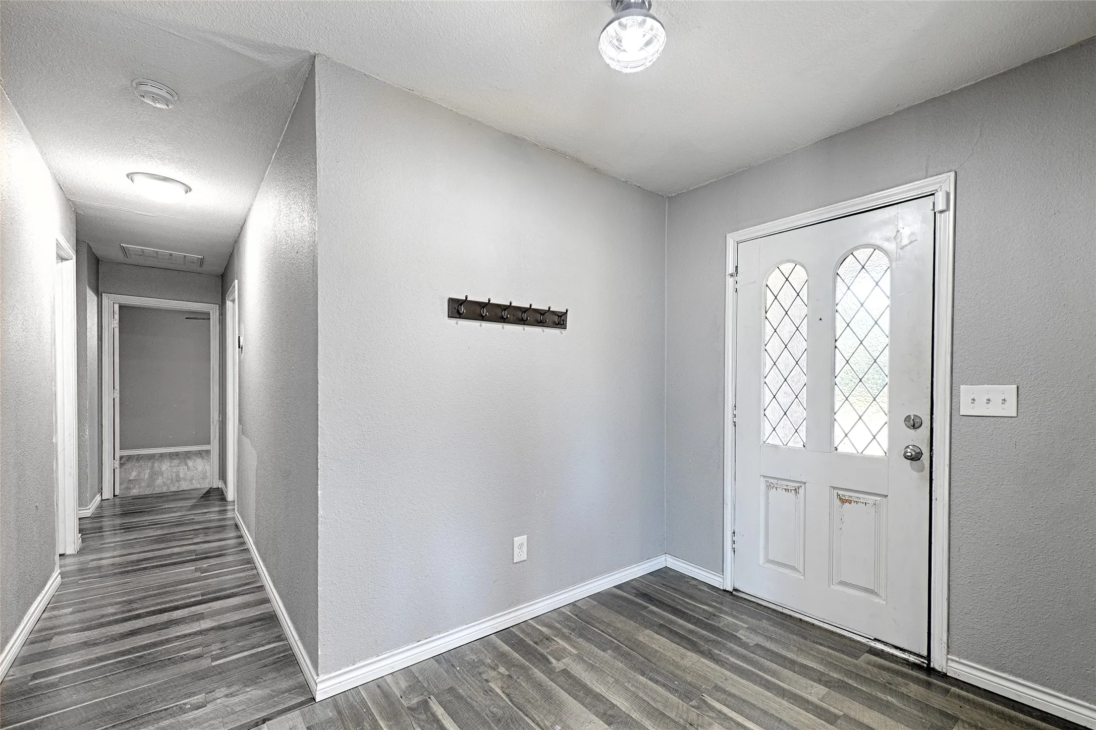 Entryway featuring a white door with decorative glass inserts, wood-finish flooring, and light-toned walls