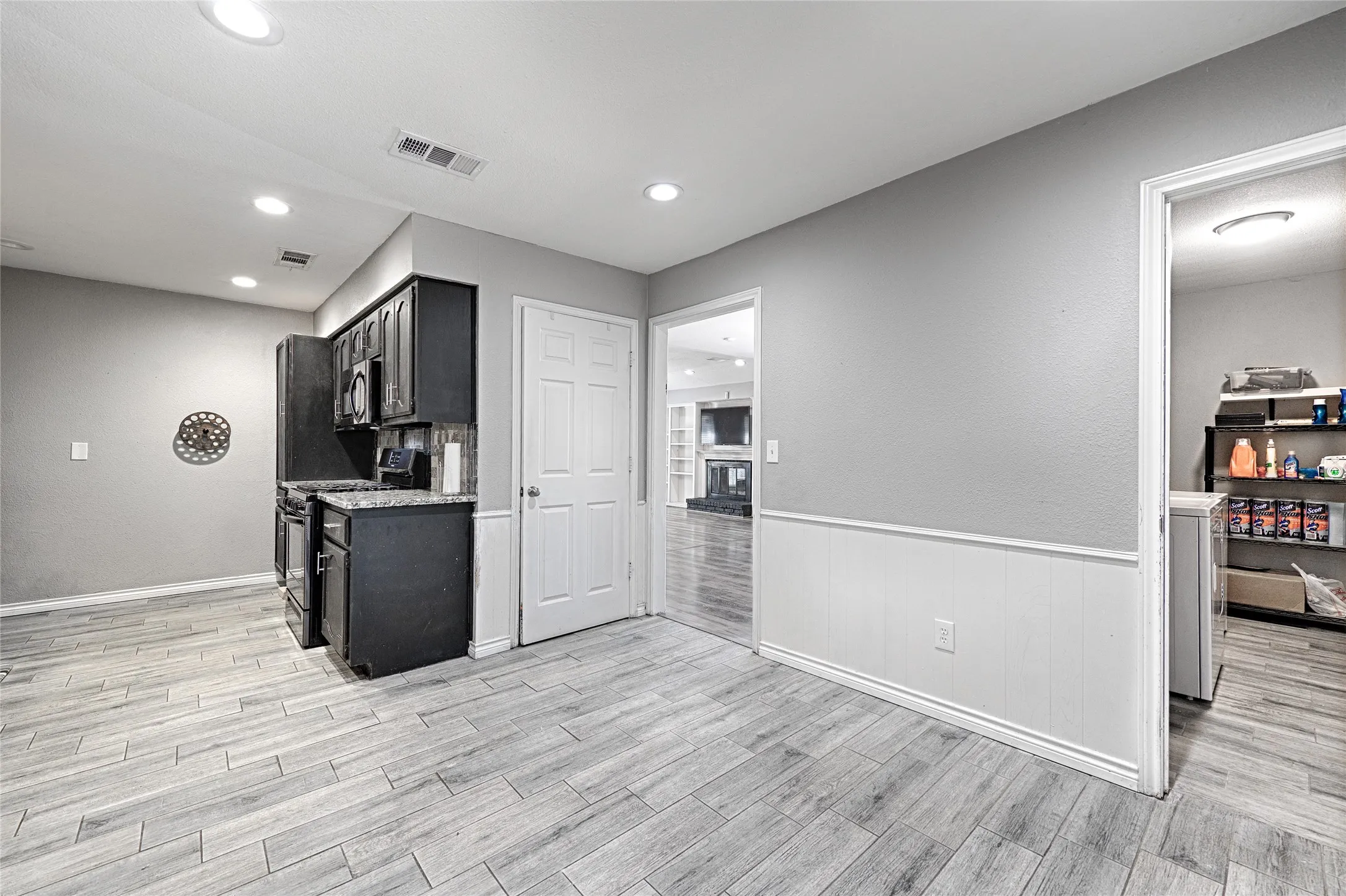 Kitchenette featuring dark-finish cabinetry, built-in appliances, wood-finish flooring, and recessed lighting