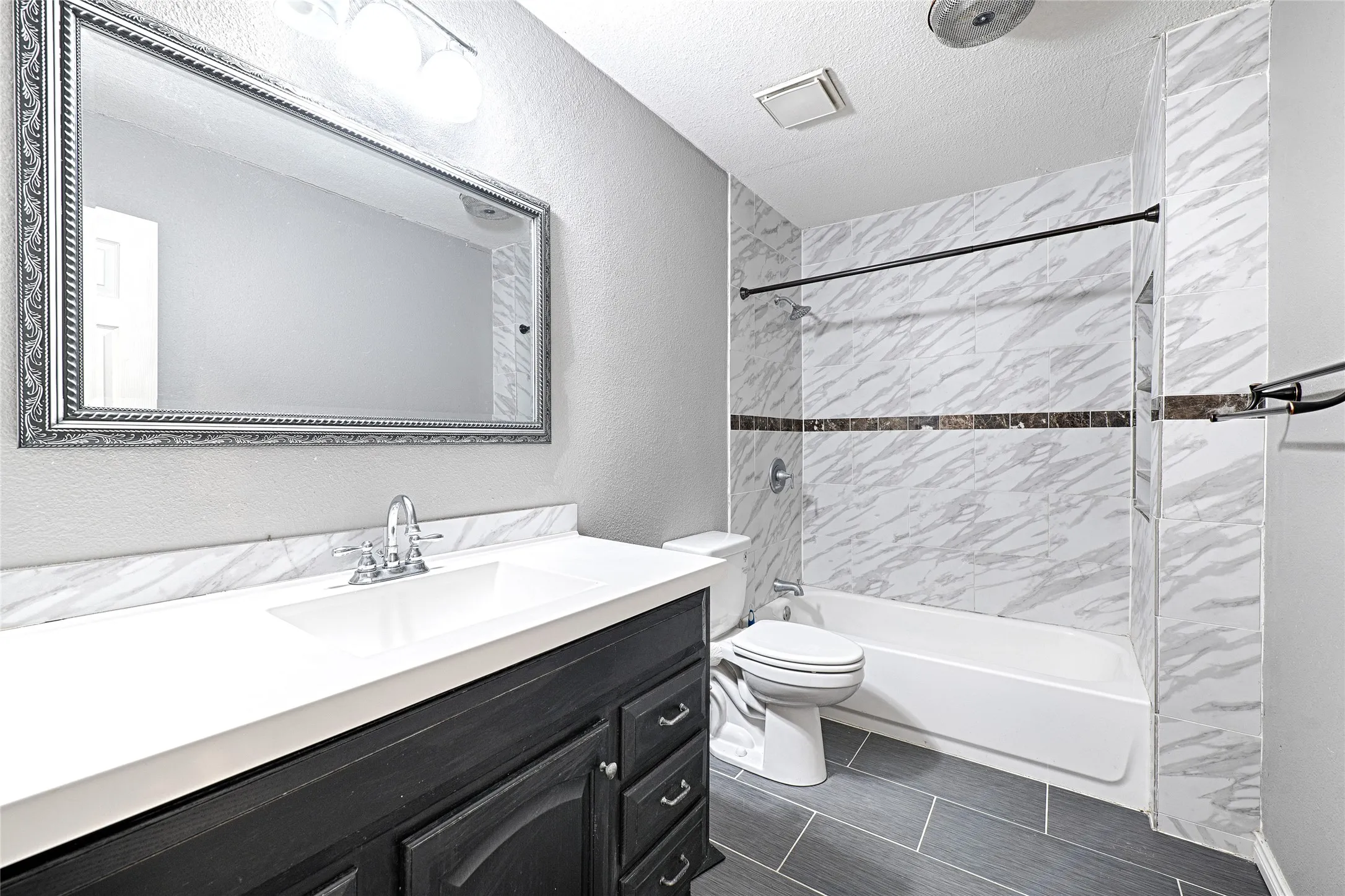 Bathroom featuring a single vanity with a white countertop, chrome faucet, and dark wood-finish cabinetry