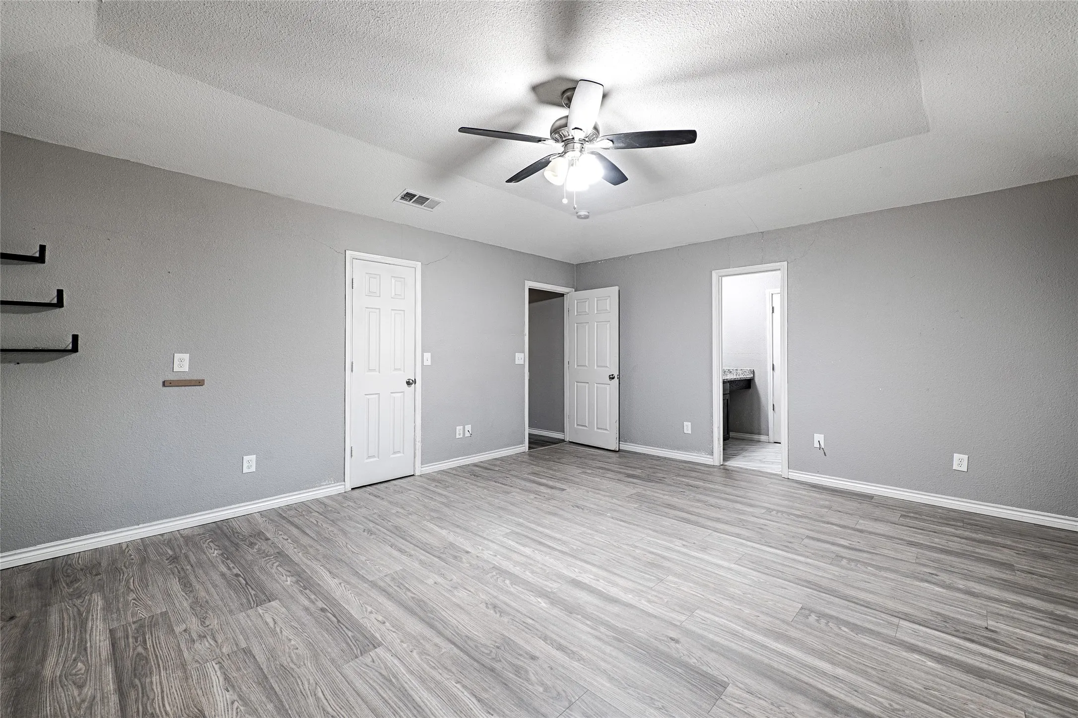 Tray ceiling with a ceiling fan, wood-finish flooring, light grey wall paint, and white trim