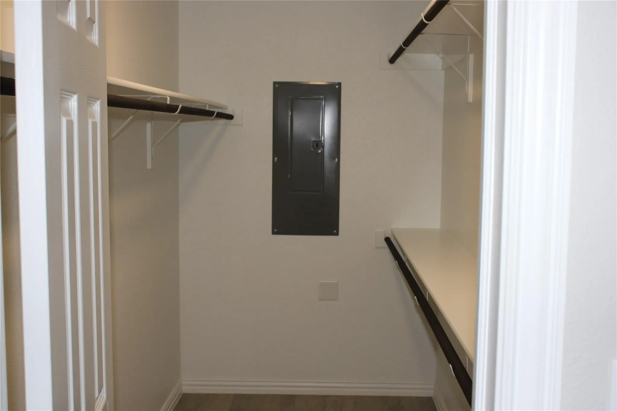 Walk-in closet with multiple white wire shelves and dark hanging rods