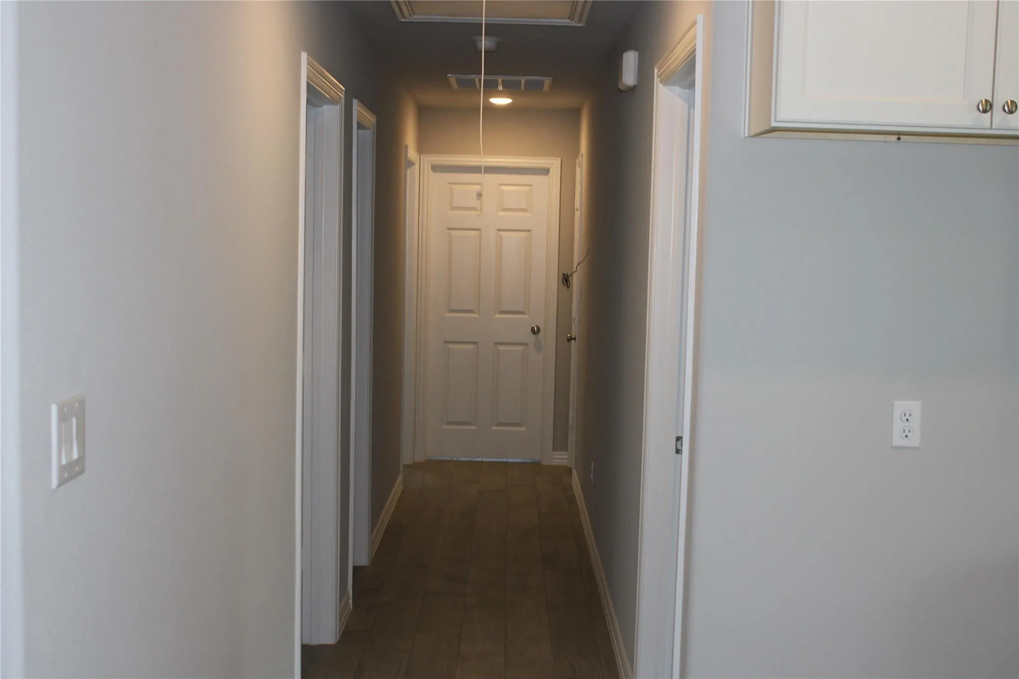 Hallway with light-colored walls, wood-finish flooring, and white paneled doors