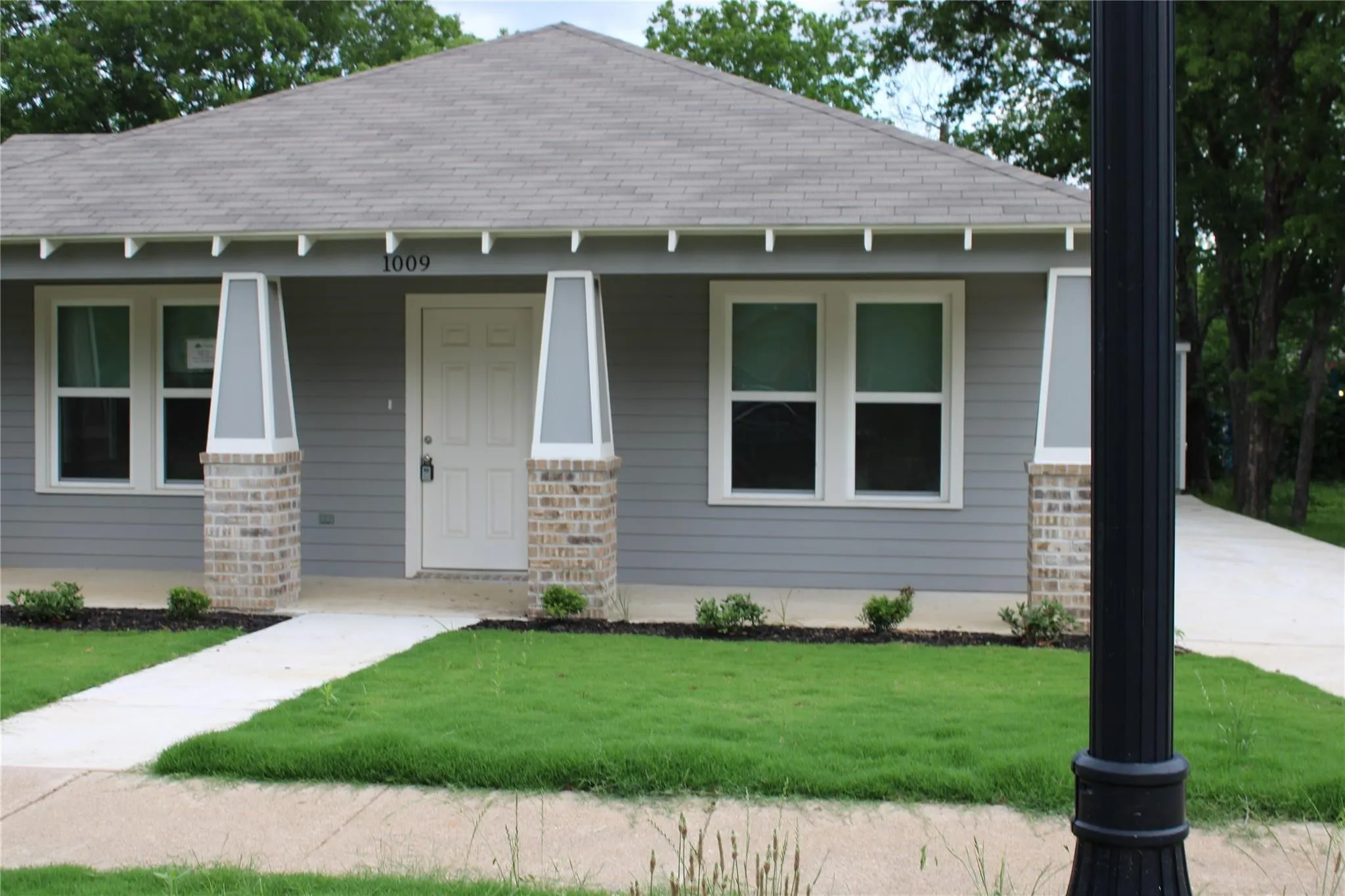 Contemporary exterior with horizontal siding, brick-clad columns, and a gabled roof