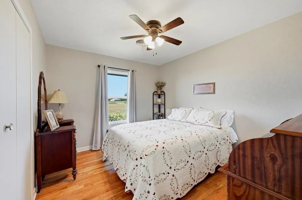 Wood-finish flooring, ceiling fan with integrated lighting, and window with outdoor scenery