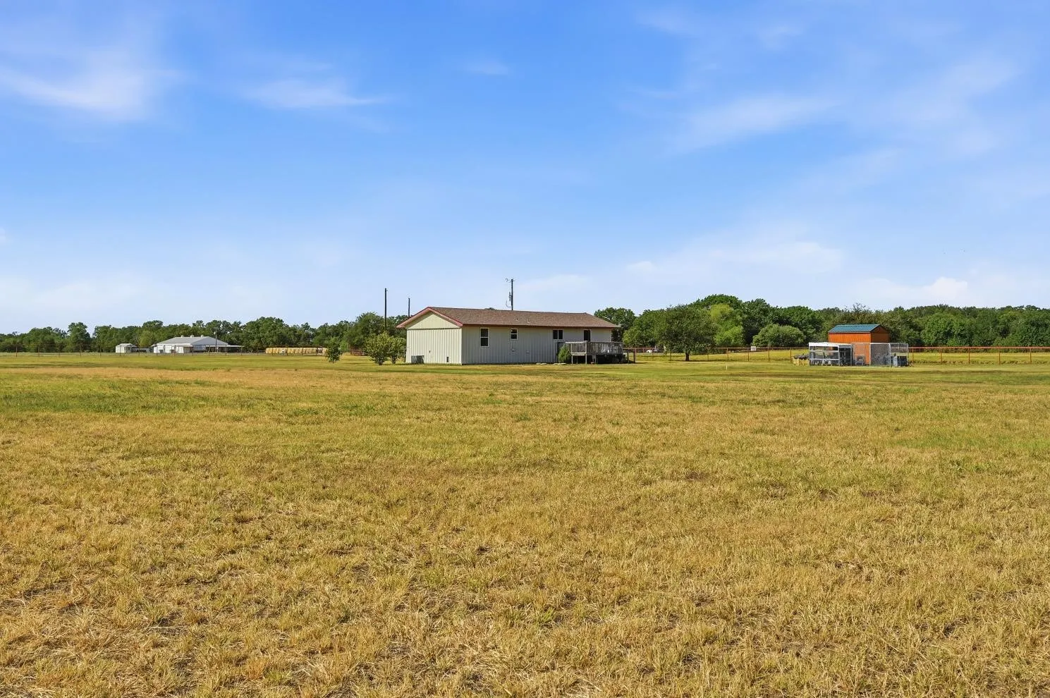 Expansive grounds featuring a detached structure and a residence with an exterior deck