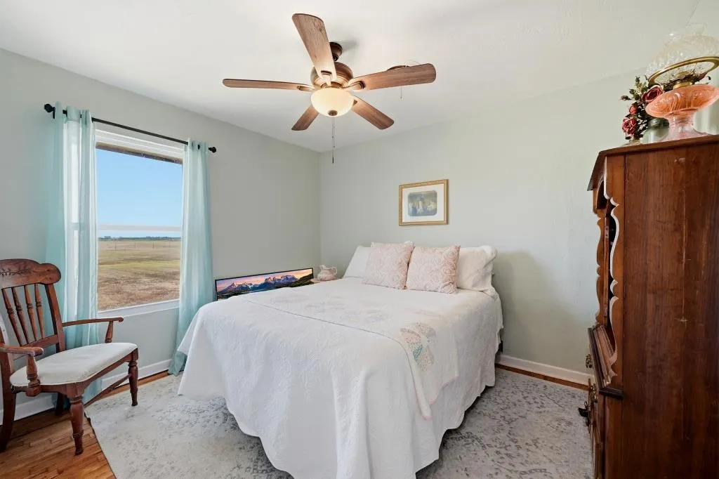 Hardwood flooring, painted walls, ceiling fan with integrated lighting, and a large window