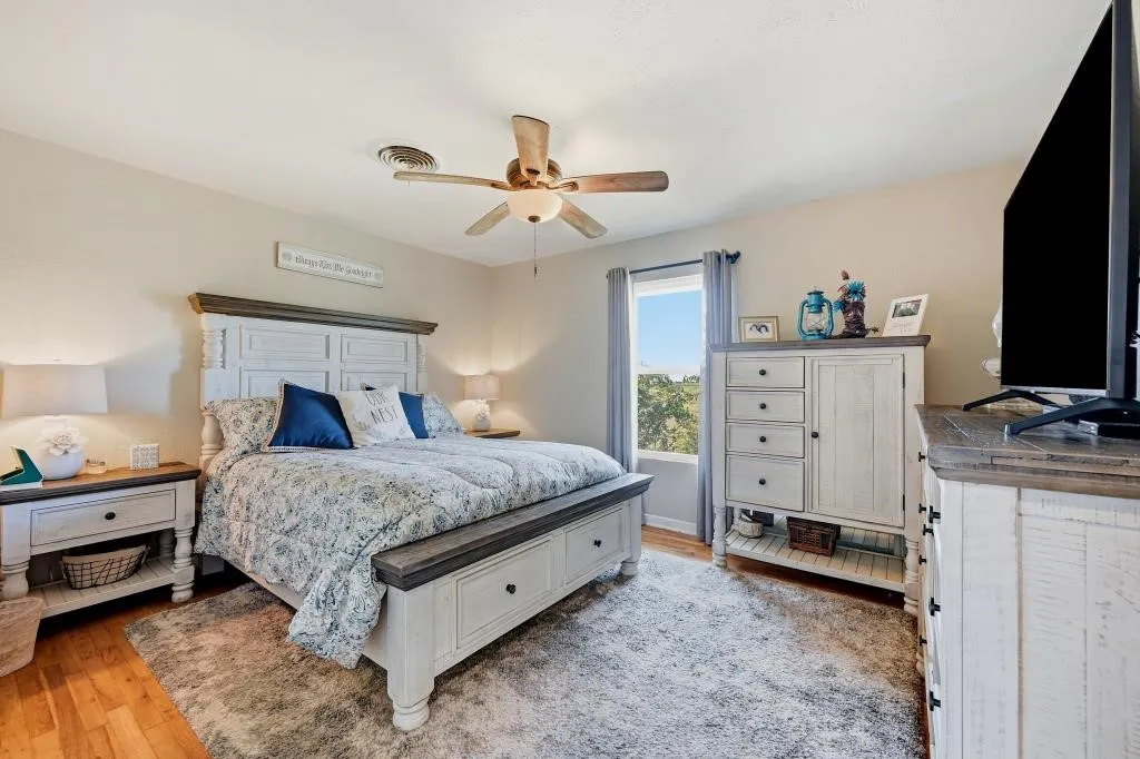 Wood-finish flooring, ceiling fan with integrated lighting, and window with outdoor scenery