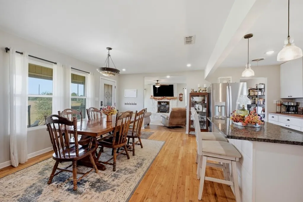 Hardwood flooring throughout, kitchen island with granite countertop, stainless steel appliances, recessed lighting, and a decorative ceiling light fixture