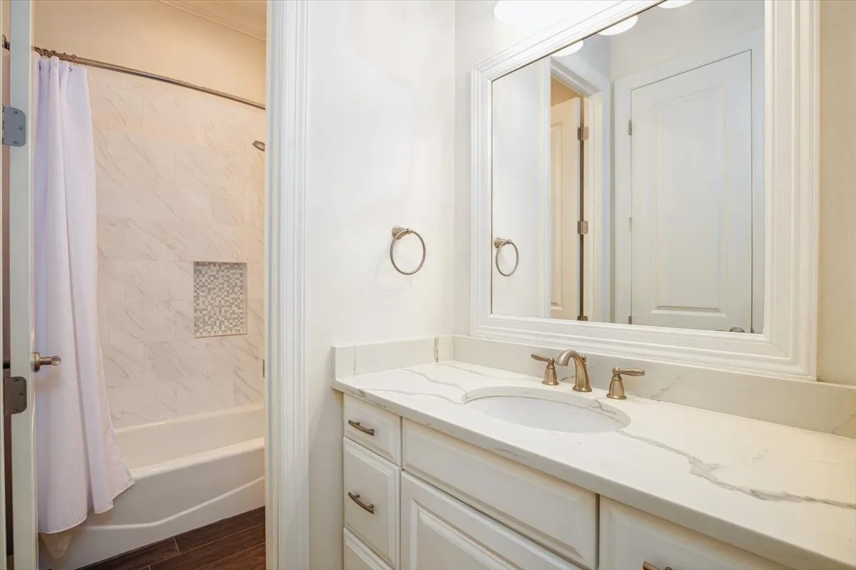 Jack and Jill Bathroom White vanity with brass fixtures, a built-in sink, and a framed mirror