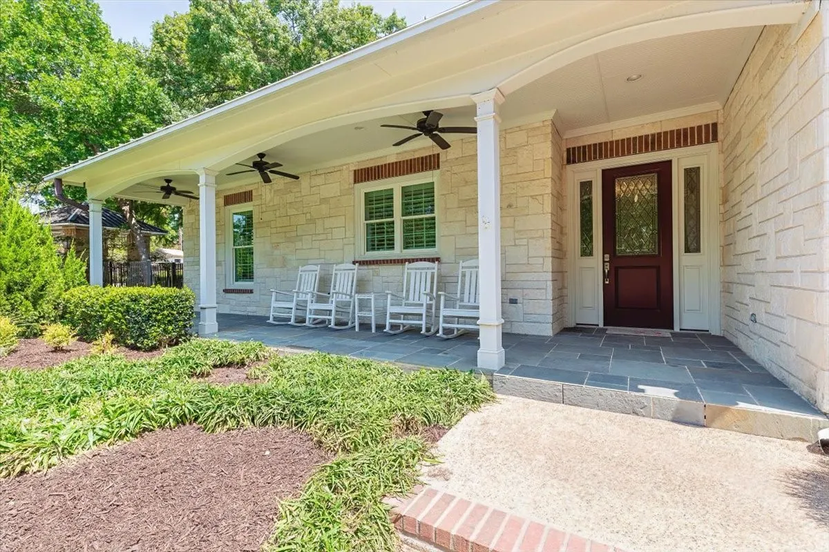 Home with a covered porch featuring multiple ceiling fans, red entry door with glass inserts, and slate tile flooring