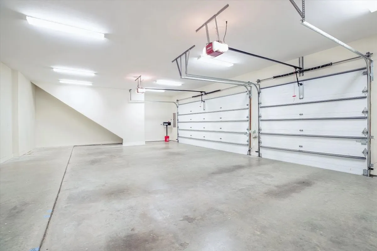 Two overhead garage doors, concrete flooring, and ceiling-mounted fluorescent lighting fixtures