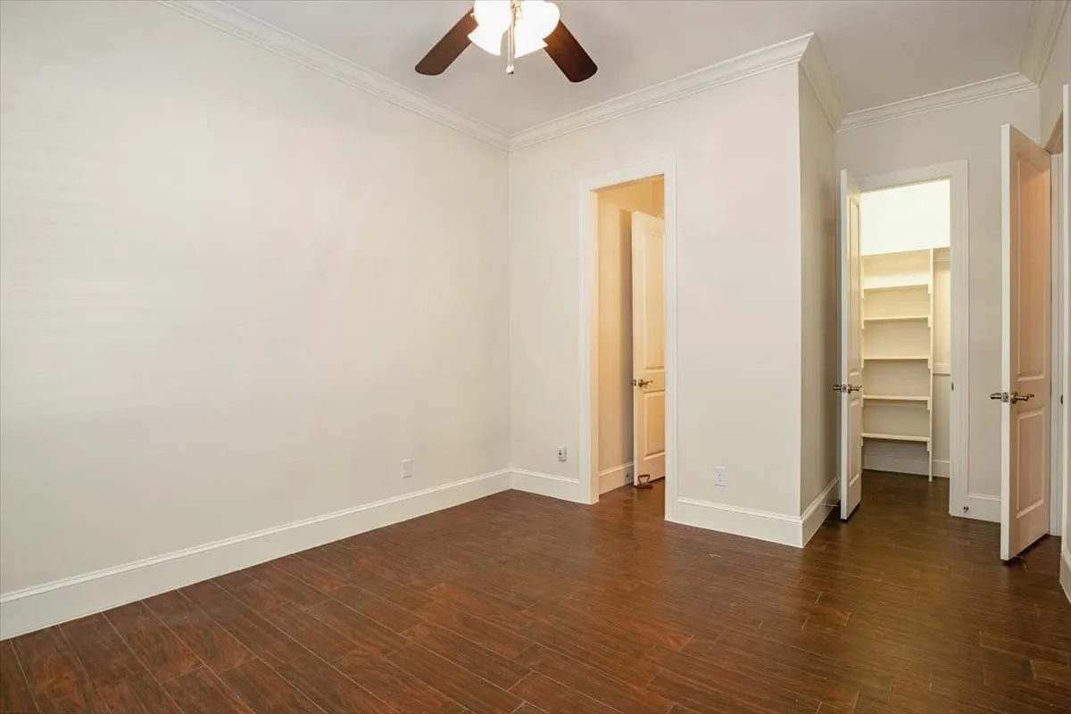 Porcelain Wood-finish flooring, crown molding, ceiling fan, and built-in closet shelving