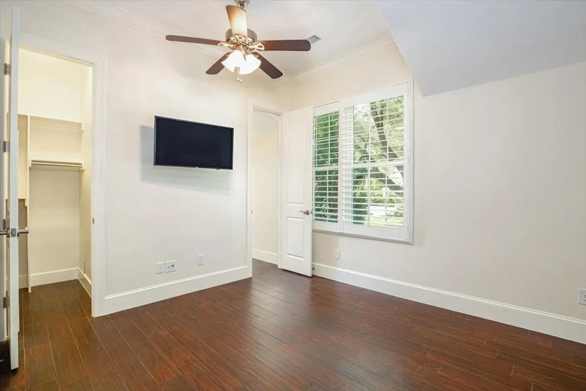 Rich porcelain wood-finish flooring, built-in closet, ceiling fan with integrated lighting, and window with plantation shutters
