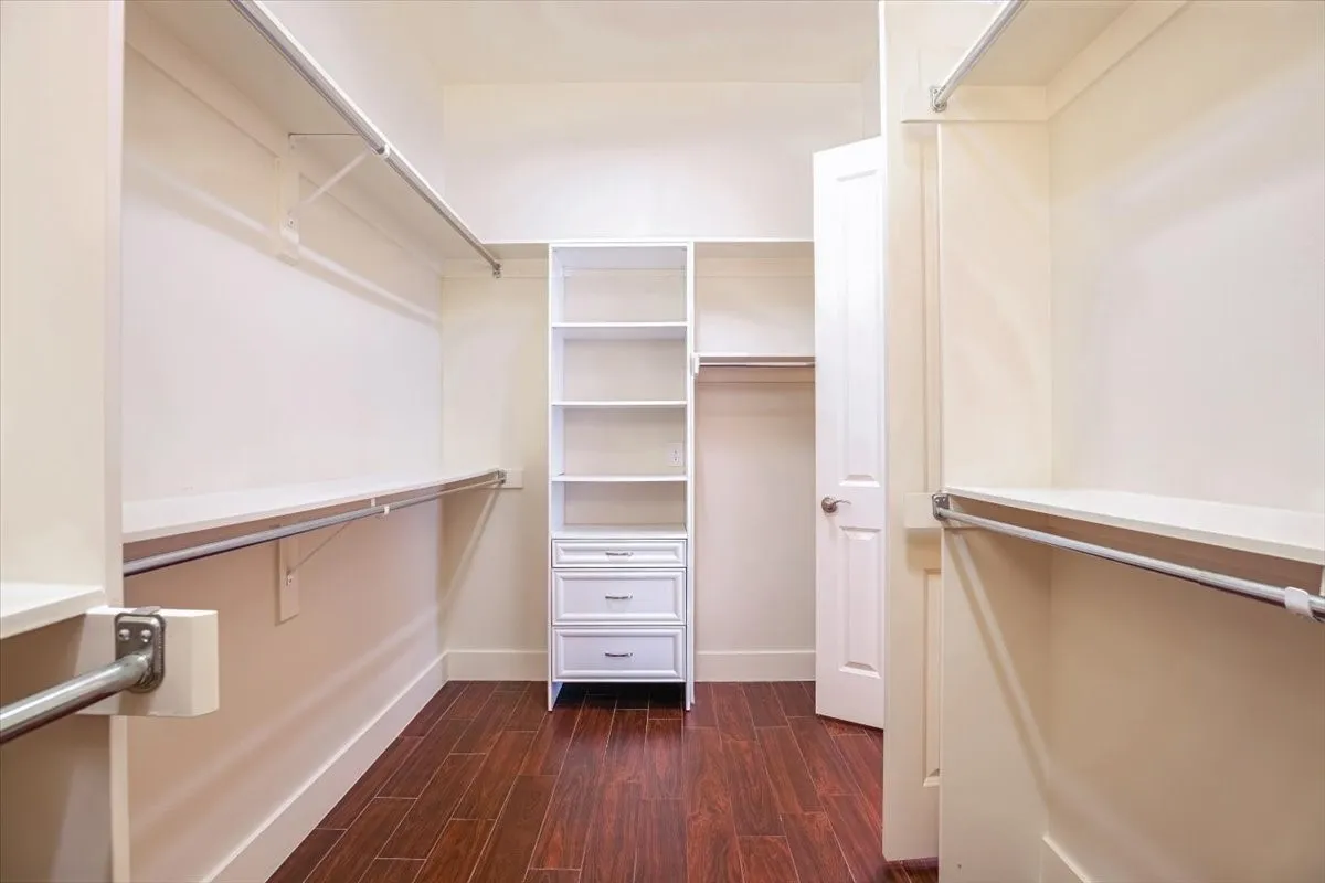Walk-in closet featuring built-in shelving, multiple hanging rods, and integrated drawers