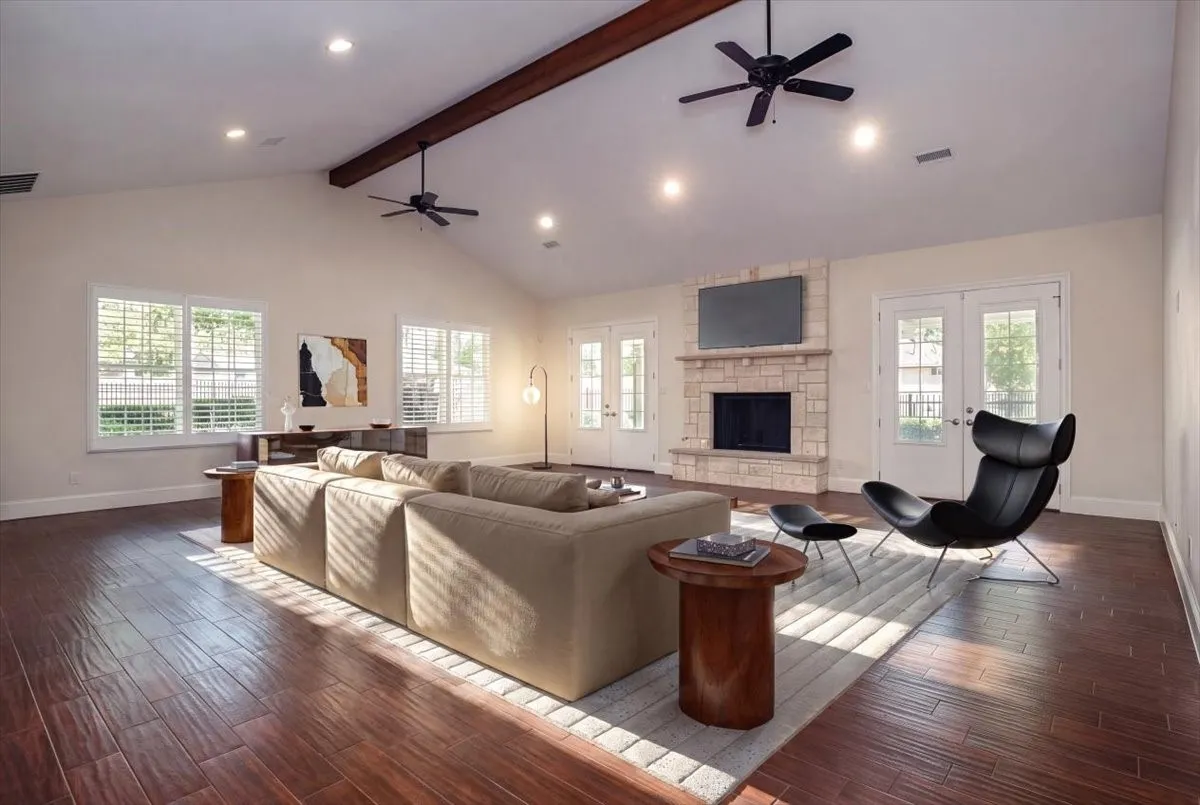 Vaulted ceiling with exposed wood beams, recessed lighting, and porcelain wood-finish flooring