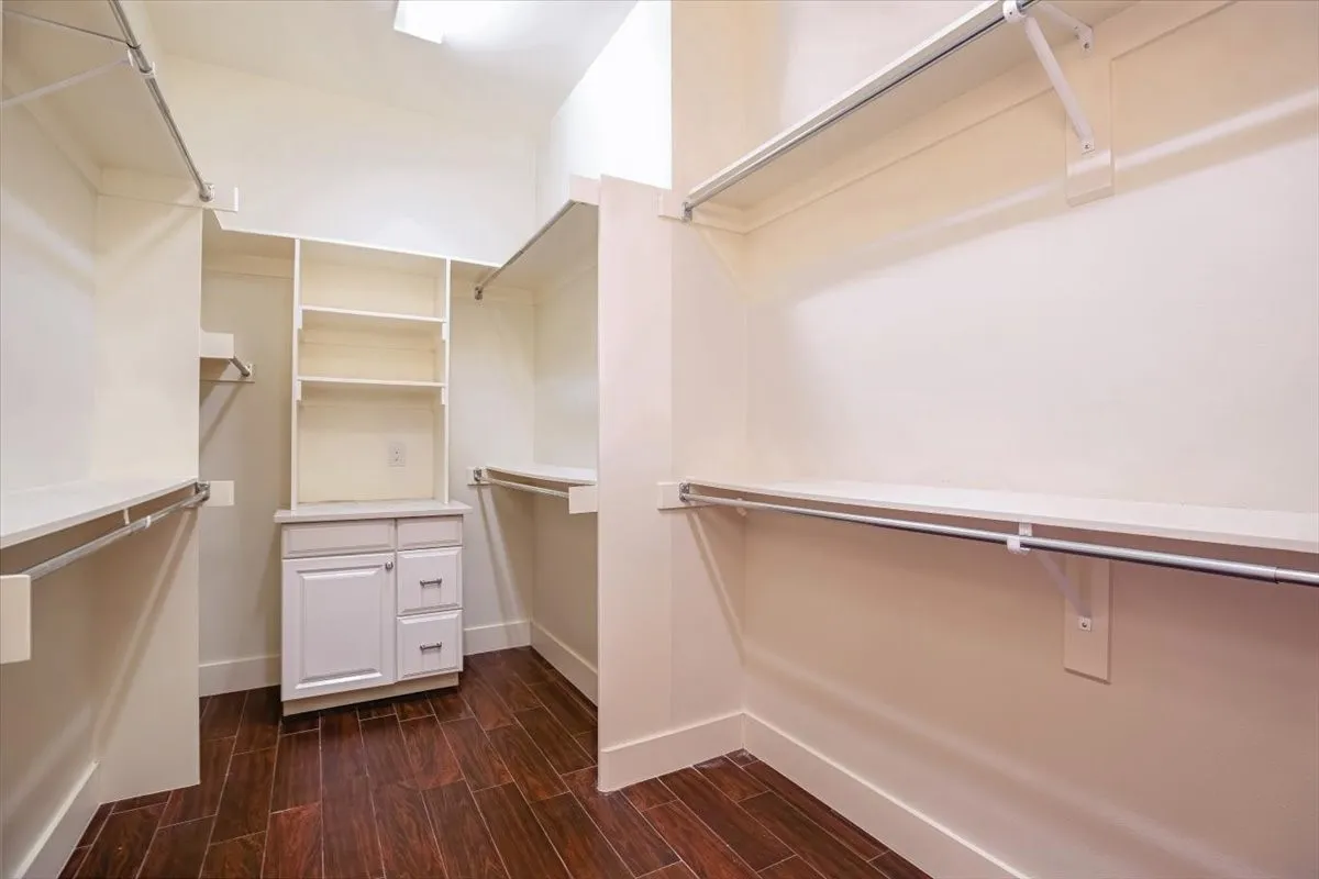 Walk-in closet featuring built-in shelving, hanging rods, and a central cabinet with drawers