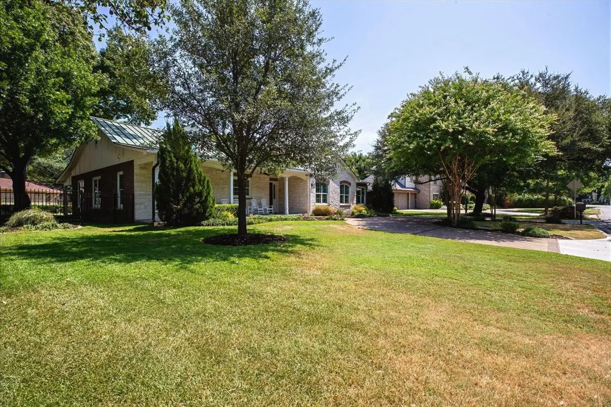 Home featuring a metal roof, covered front porch, mature trees, and a concrete driveway