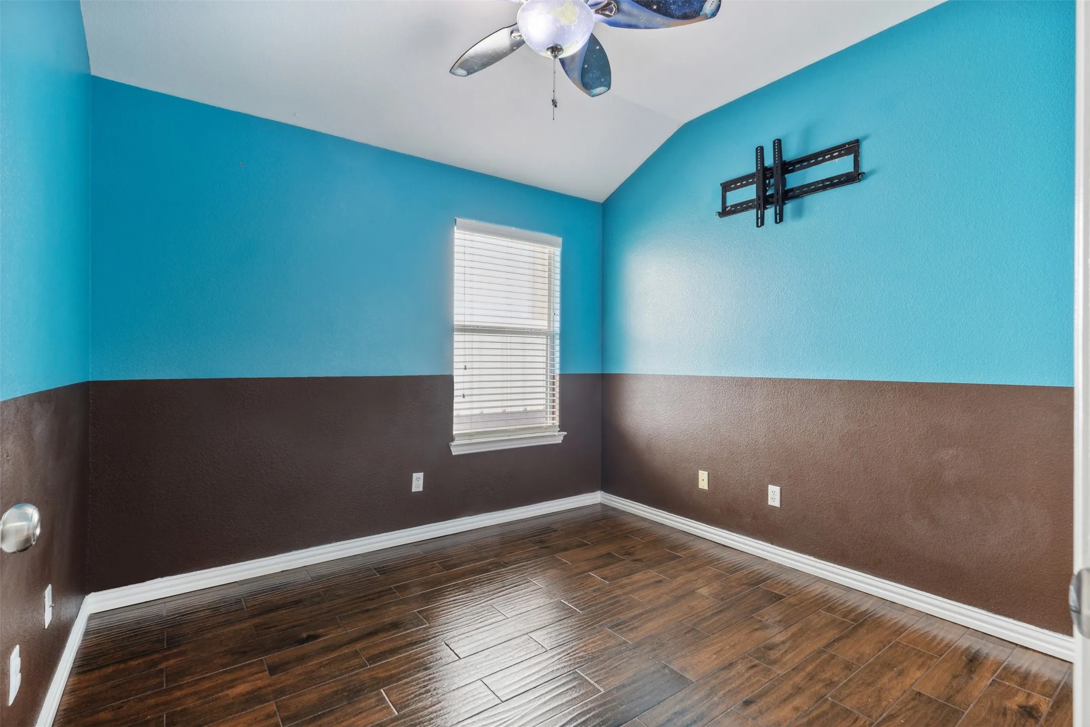 Empty room featuring dark hardwood / wood-style flooring, ceiling fan, and lofted ceiling