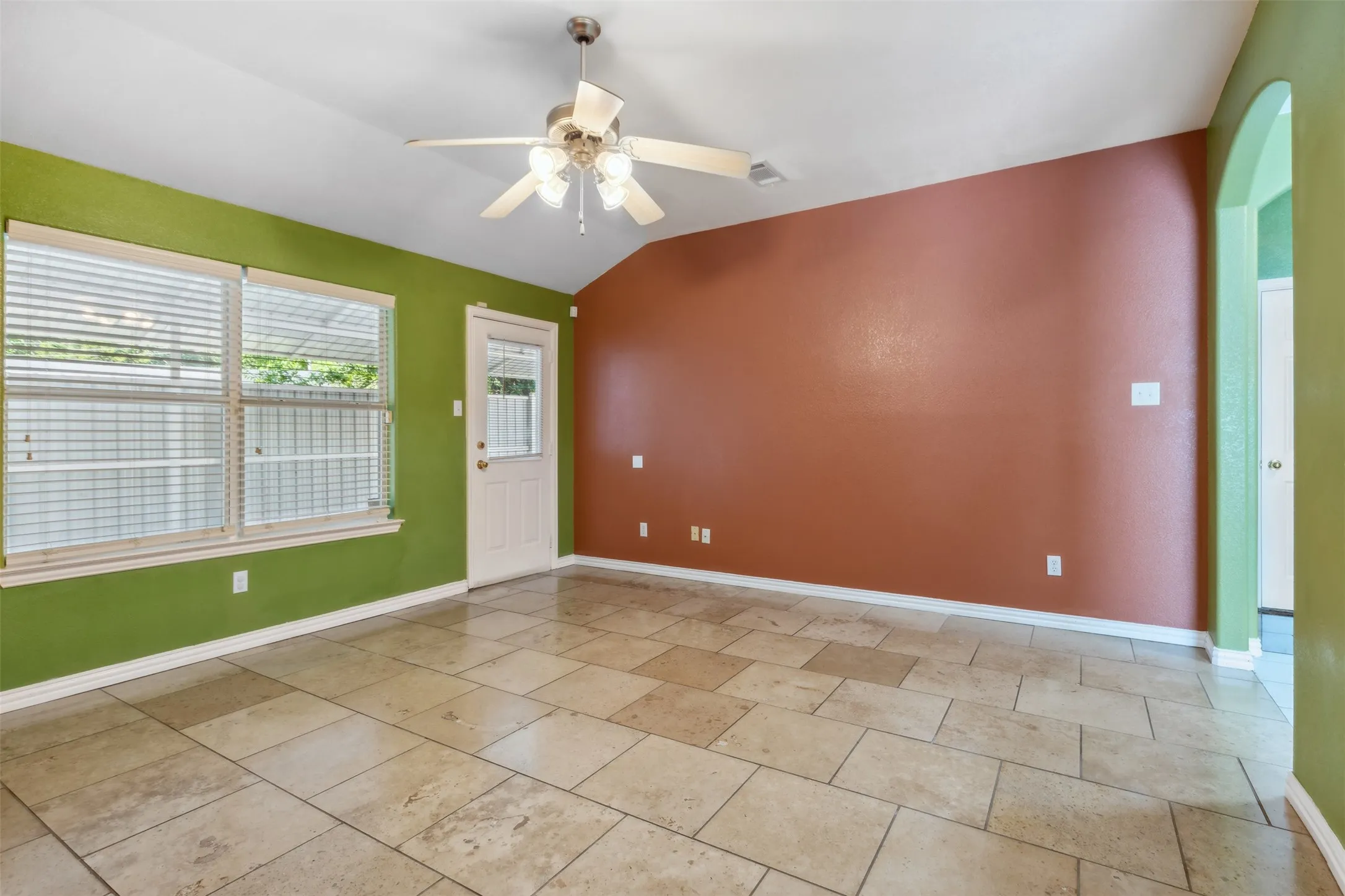Tiled spare room featuring lofted ceiling and ceiling fan