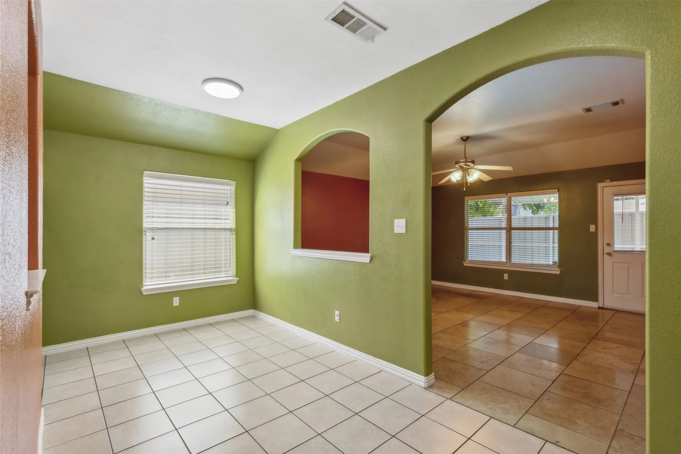 Empty room with ceiling fan and light tile flooring