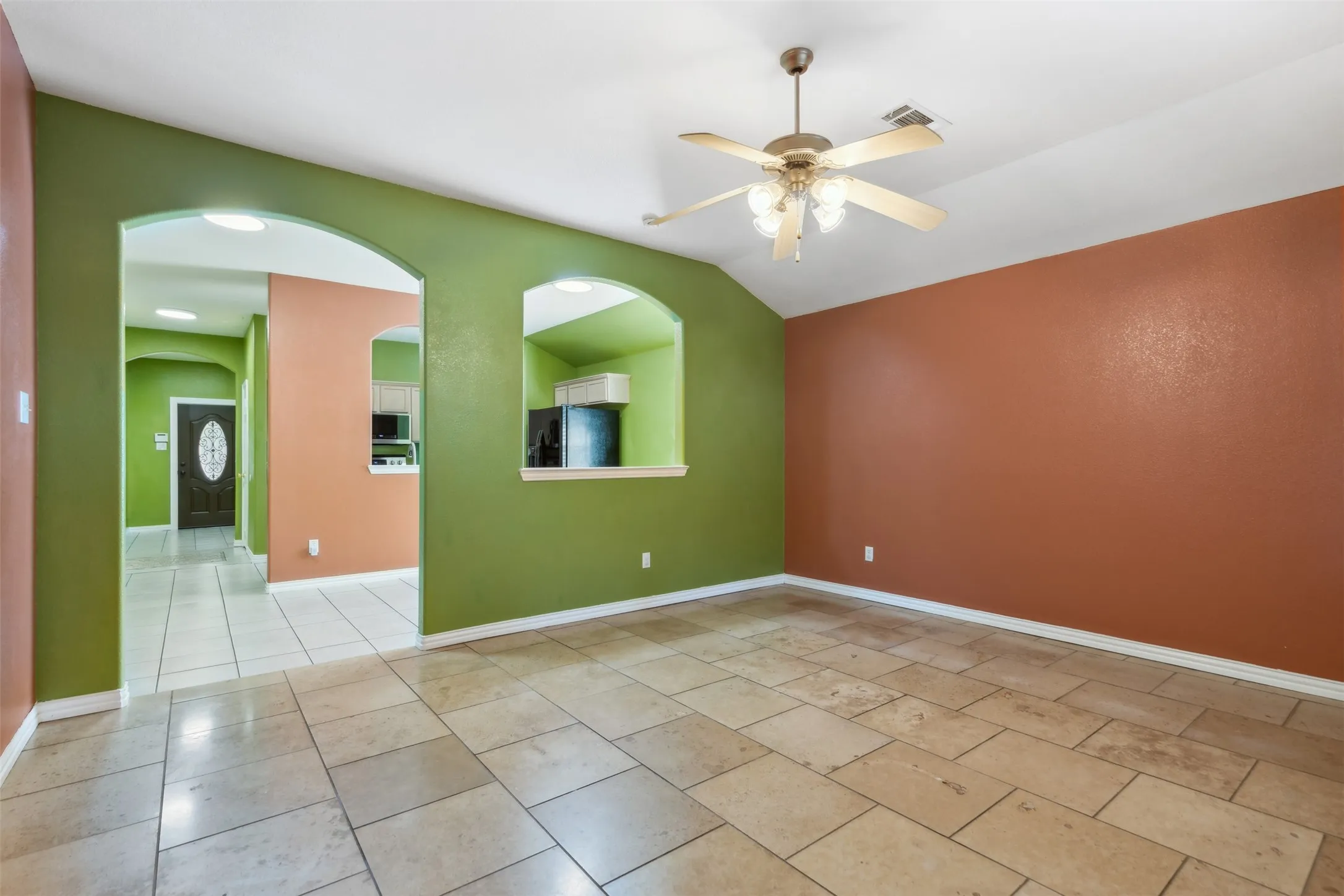 Unfurnished room with vaulted ceiling, ceiling fan, and light tile floors