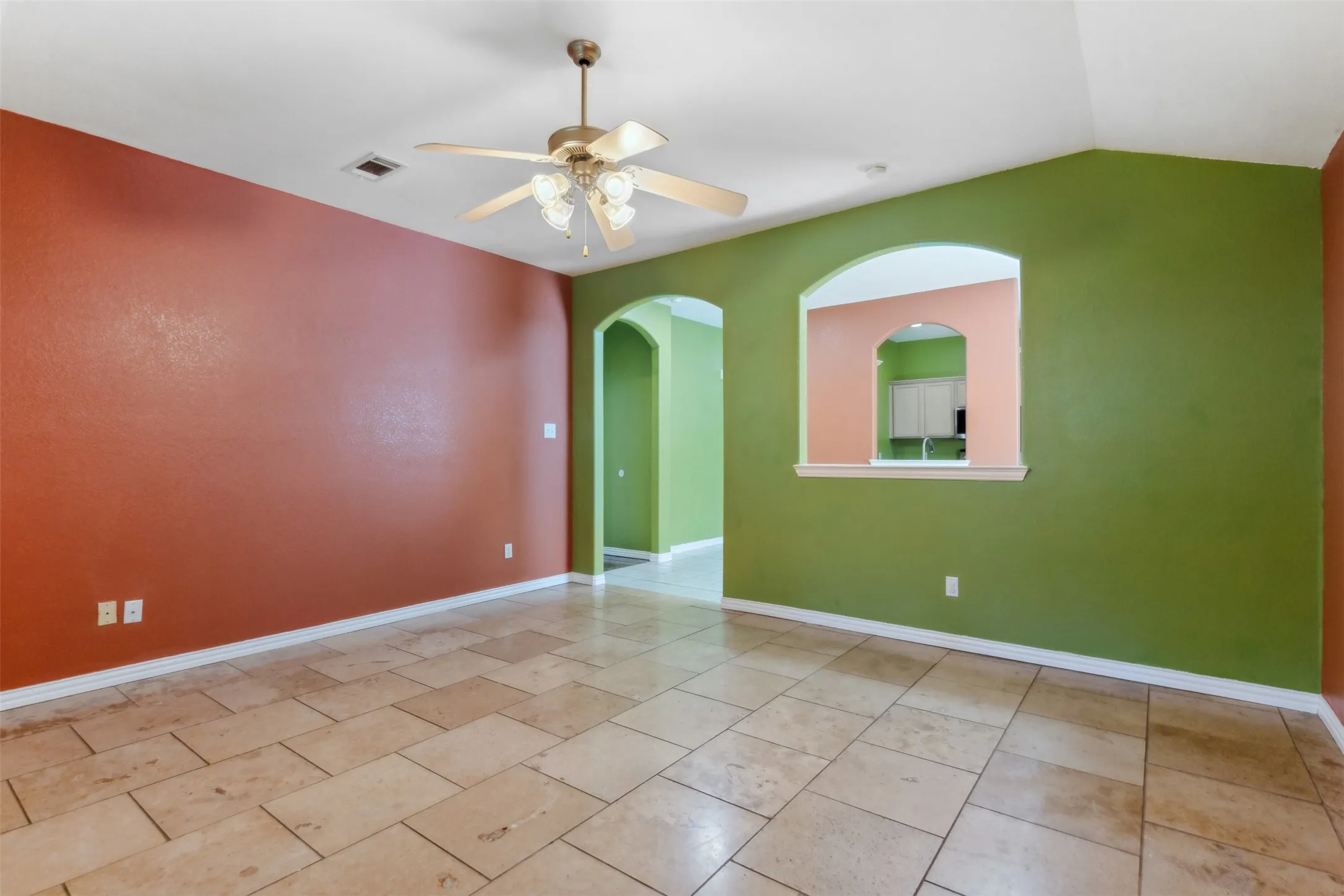Tiled empty room with lofted ceiling and ceiling fan