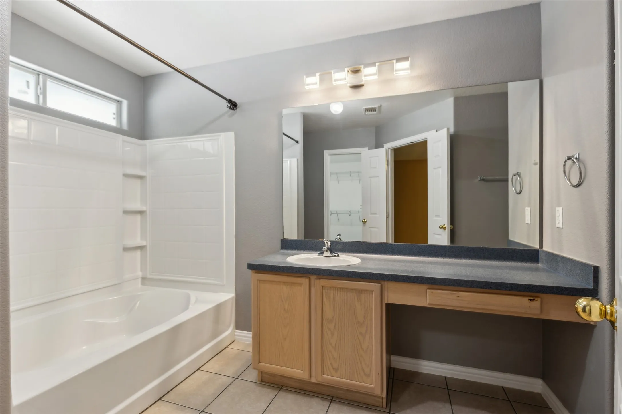 Bathroom with bathing tub / shower combination, tile flooring, and vanity with extensive cabinet space