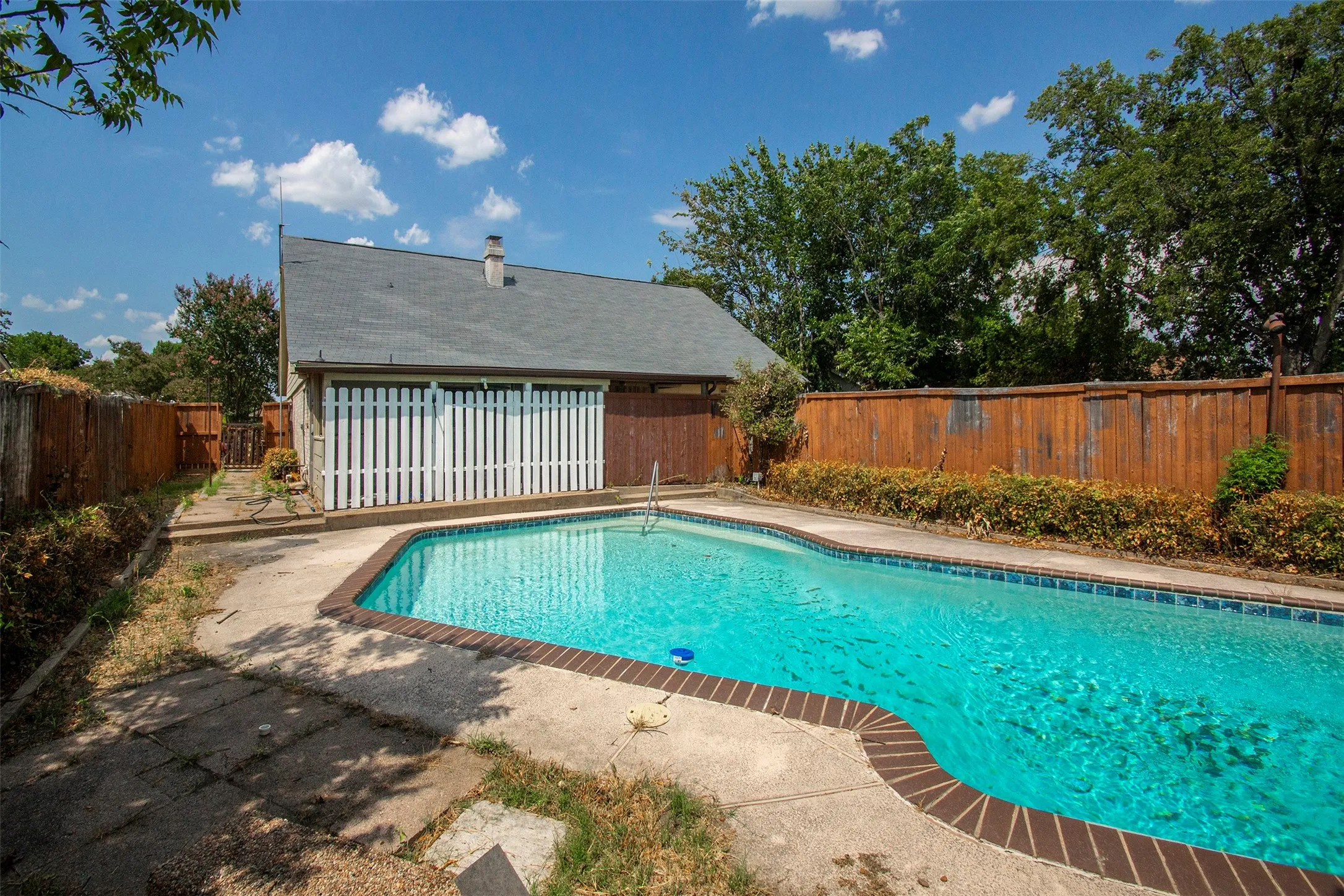In-ground swimming pool with brick coping and concrete surround