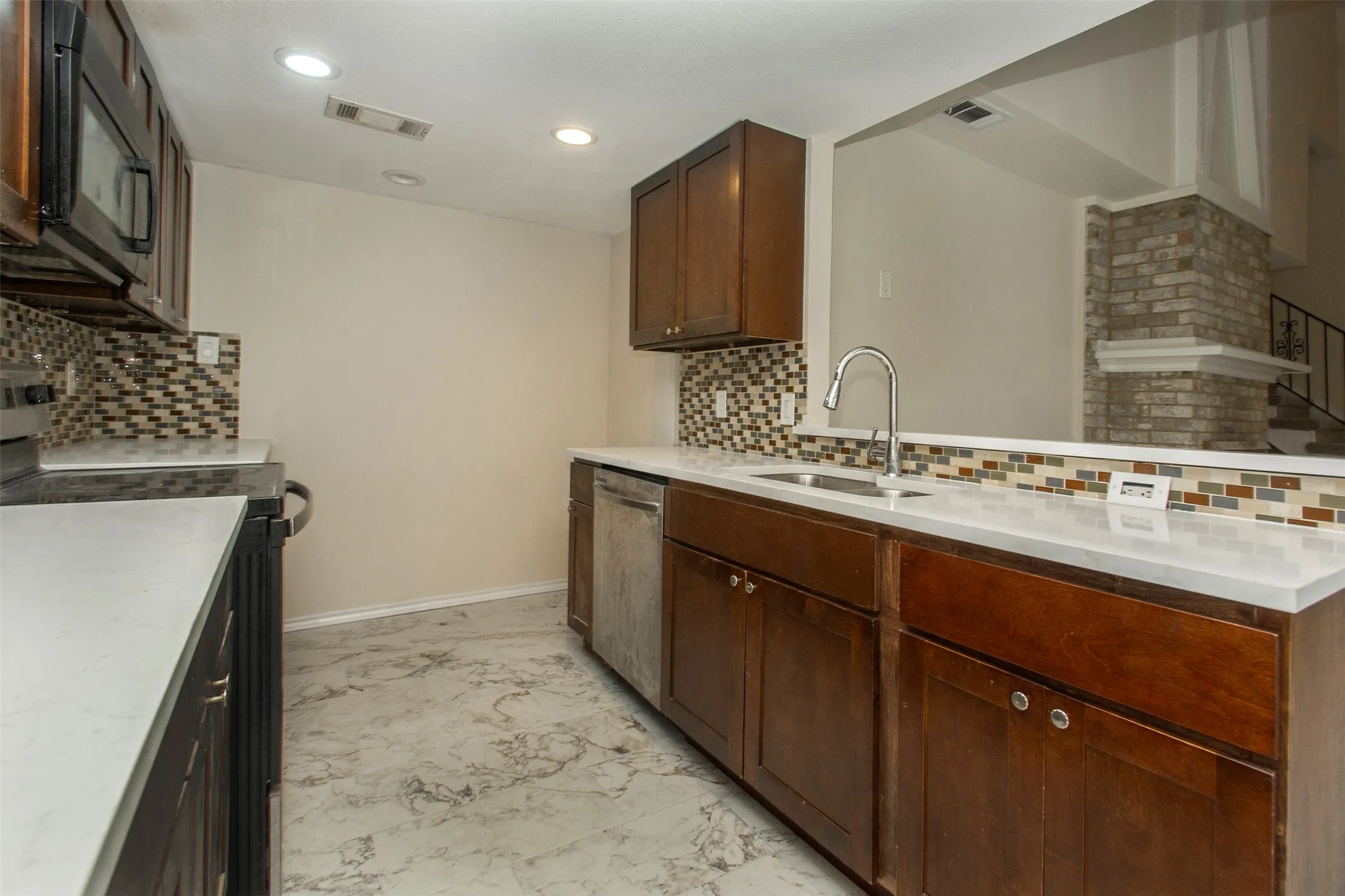 Kitchen featuring wood cabinetry, white countertops, stainless steel sink, mosaic tile backsplash, and recessed lighting
