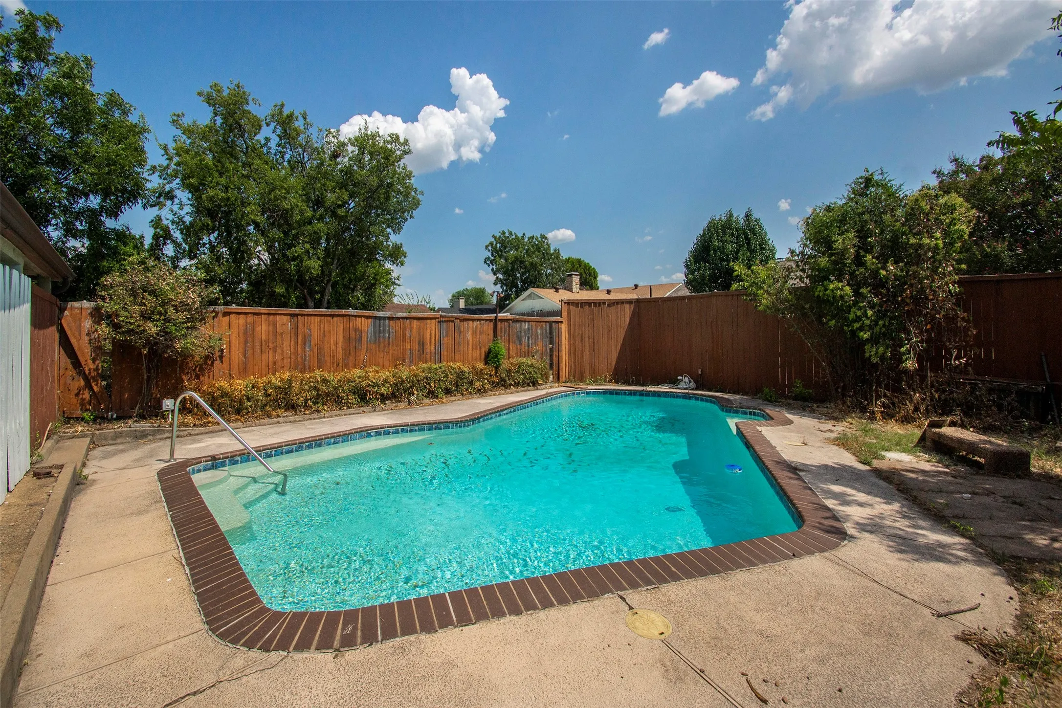 In-ground swimming pool featuring a brick coping and concrete surround