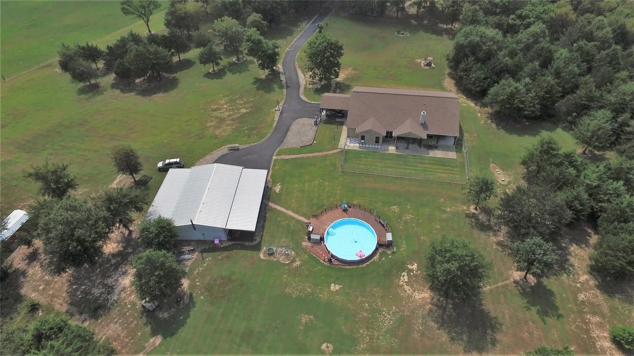 HUGE METAL 30x50 WORKSHOP with 2 covered carports for the tractors and trailers. View of Pool & Fenced Back Yard