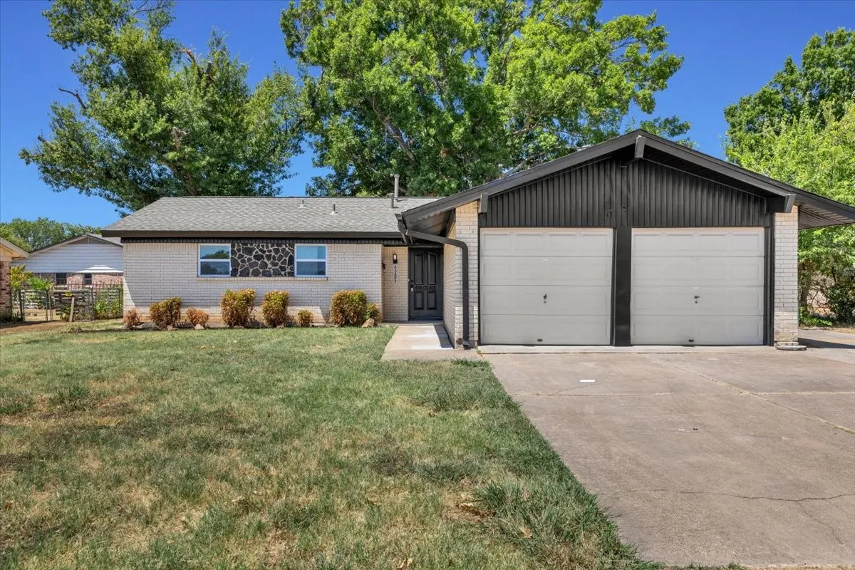 Brick exterior with a two-car garage, mature landscaping, and a concrete driveway