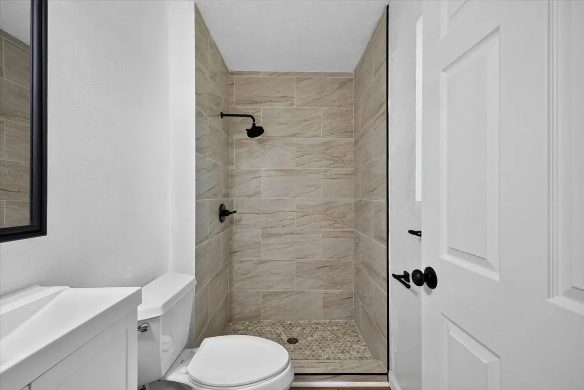 Walk-in shower with tiled walls and pebble-finish flooring