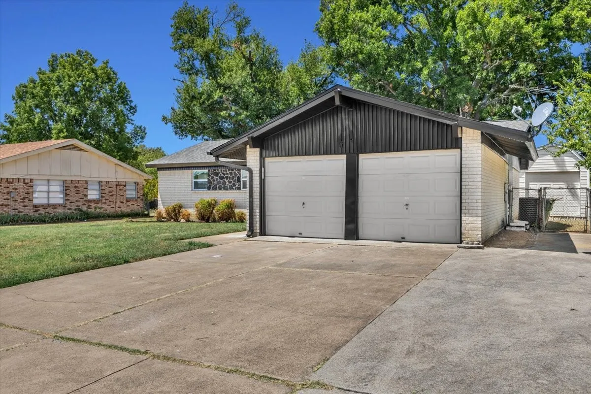 Two-car garage with white paneled doors, black vertical siding, and white brick detailing