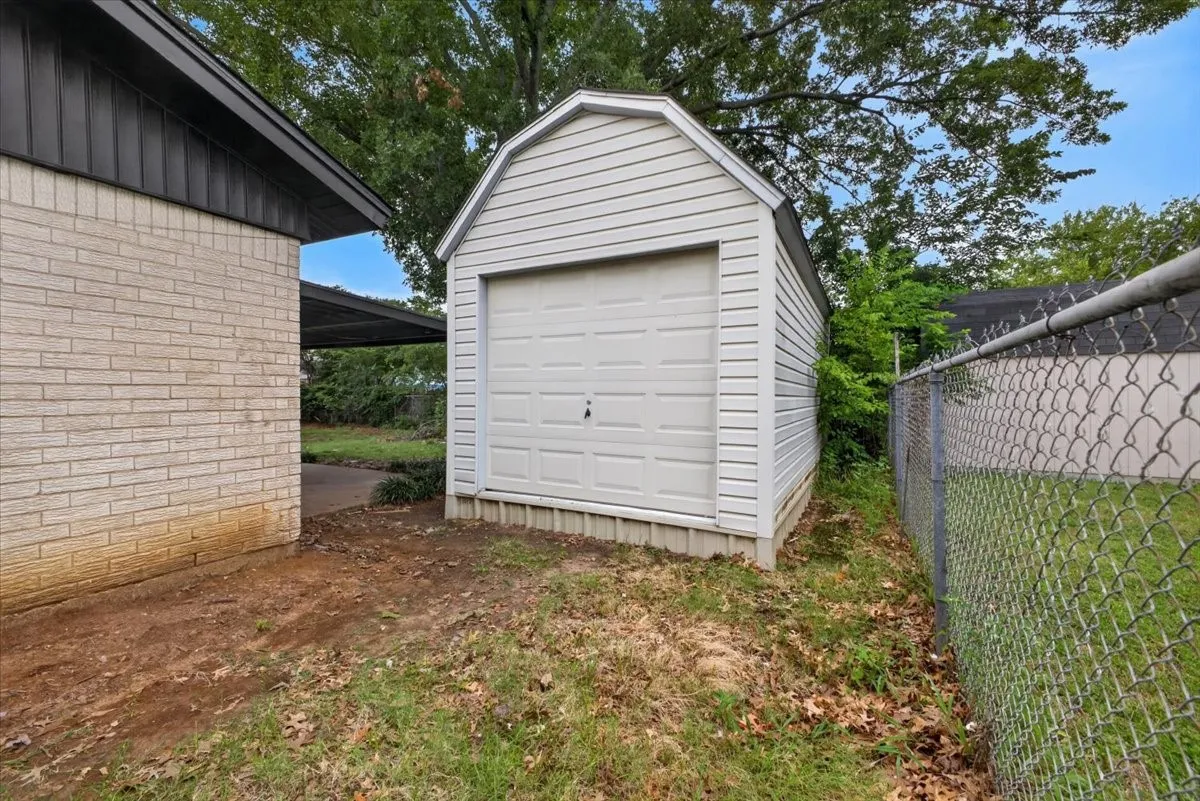 Detached outbuilding with an overhead door, vinyl siding, and a gambrel roof