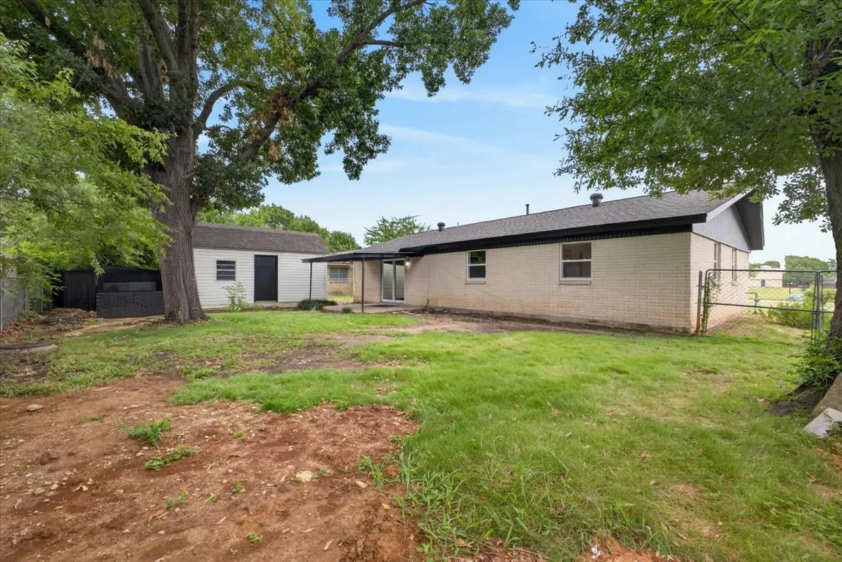 Expansive backyard featuring a detached storage shed, privacy fencing, and a covered patio area
