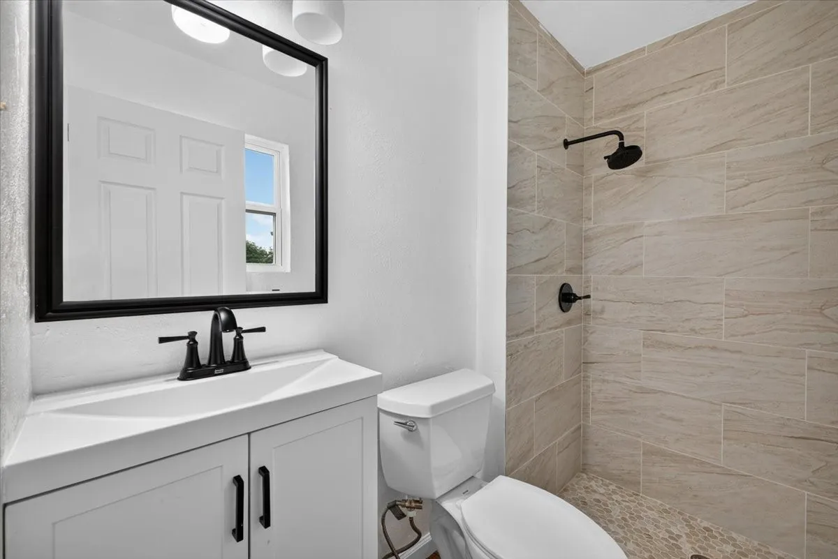 White vanity with black hardware, black framed mirror, and black faucet