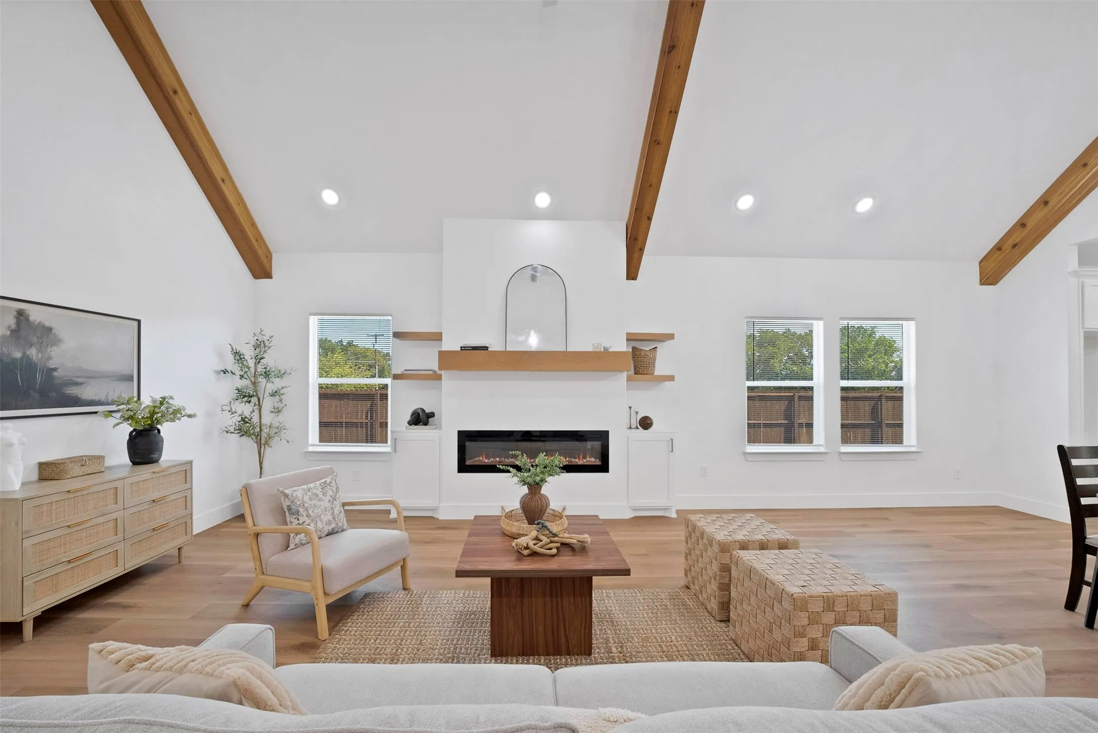 Vaulted ceilings with exposed wood beams, wood-finish flooring, a built-in fireplace, and white cabinetry