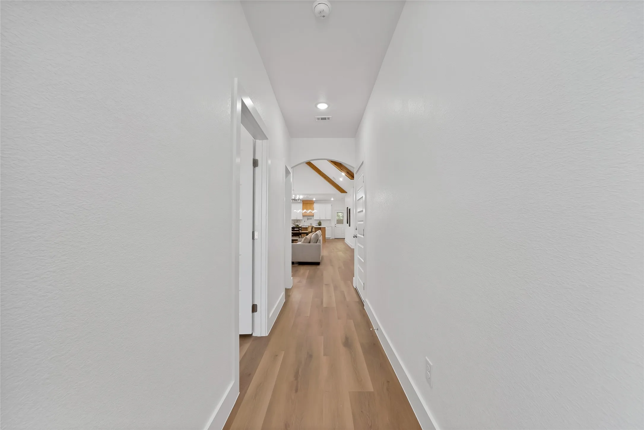 Hallway with wood-finish flooring, recessed lighting, and an arched doorway