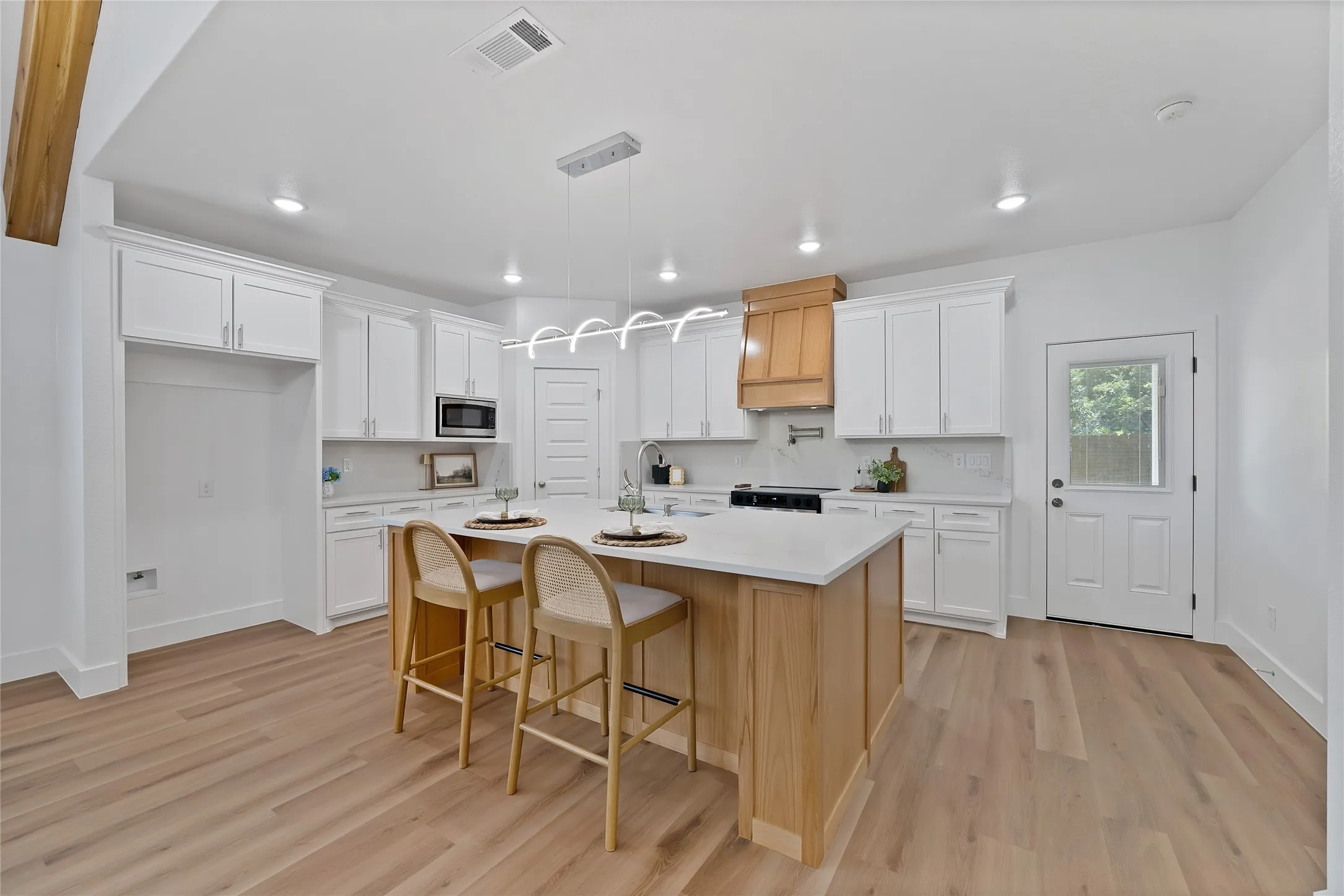 Kitchen featuring a central island with countertop, white cabinetry, wood-finish flooring, recessed lighting, and a modern chandelier