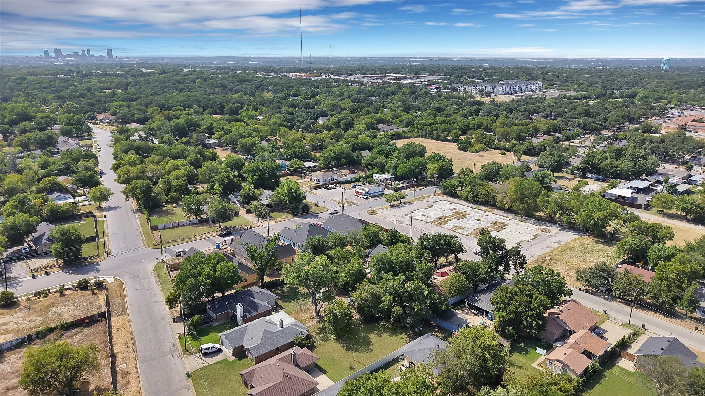 Residential properties with mature trees, established streets, and an urban skyline in the distance