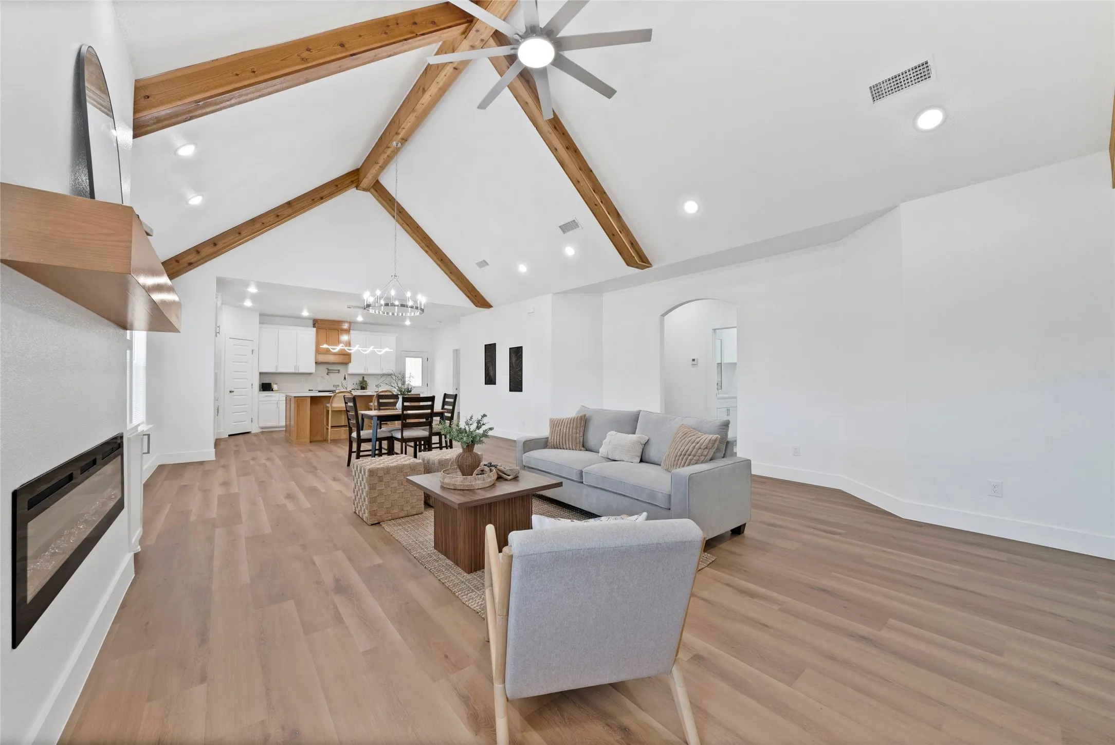 Vaulted ceiling with exposed wood beams, recessed lighting, and wood-finish flooring
